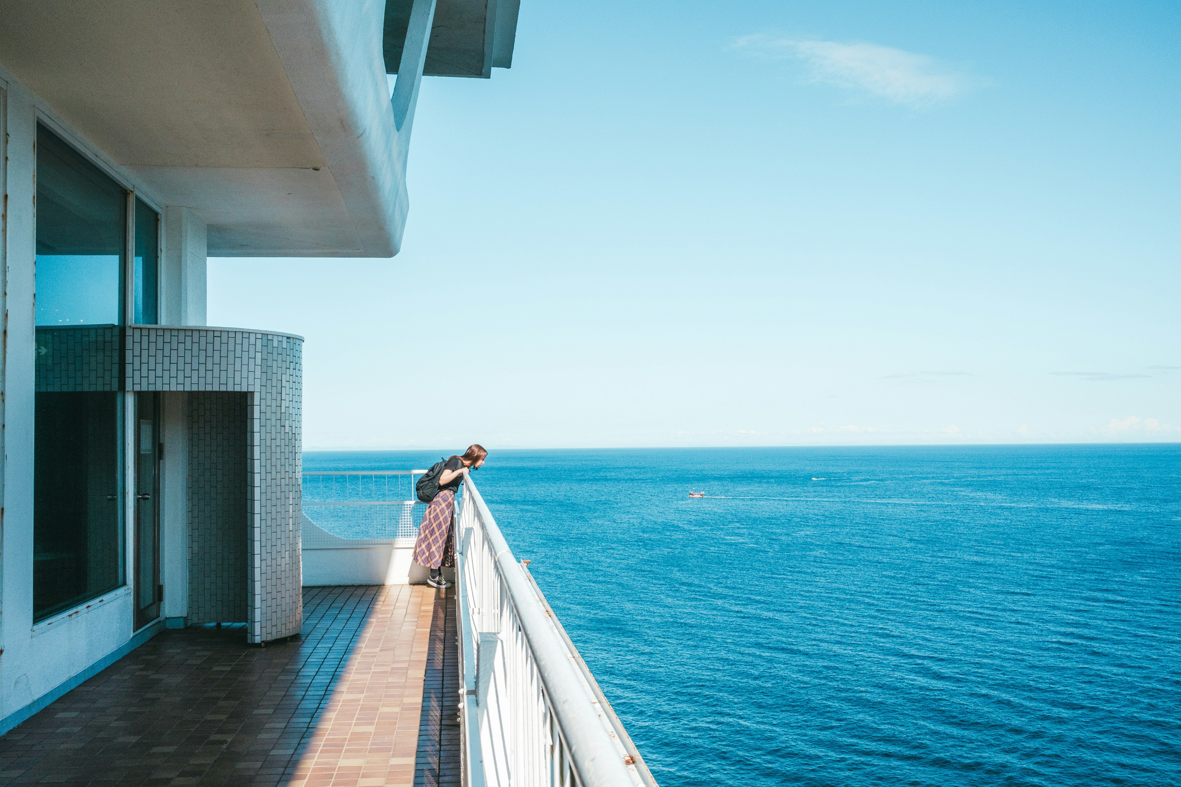 Femme penchée sur un balcon surplombant l'océan