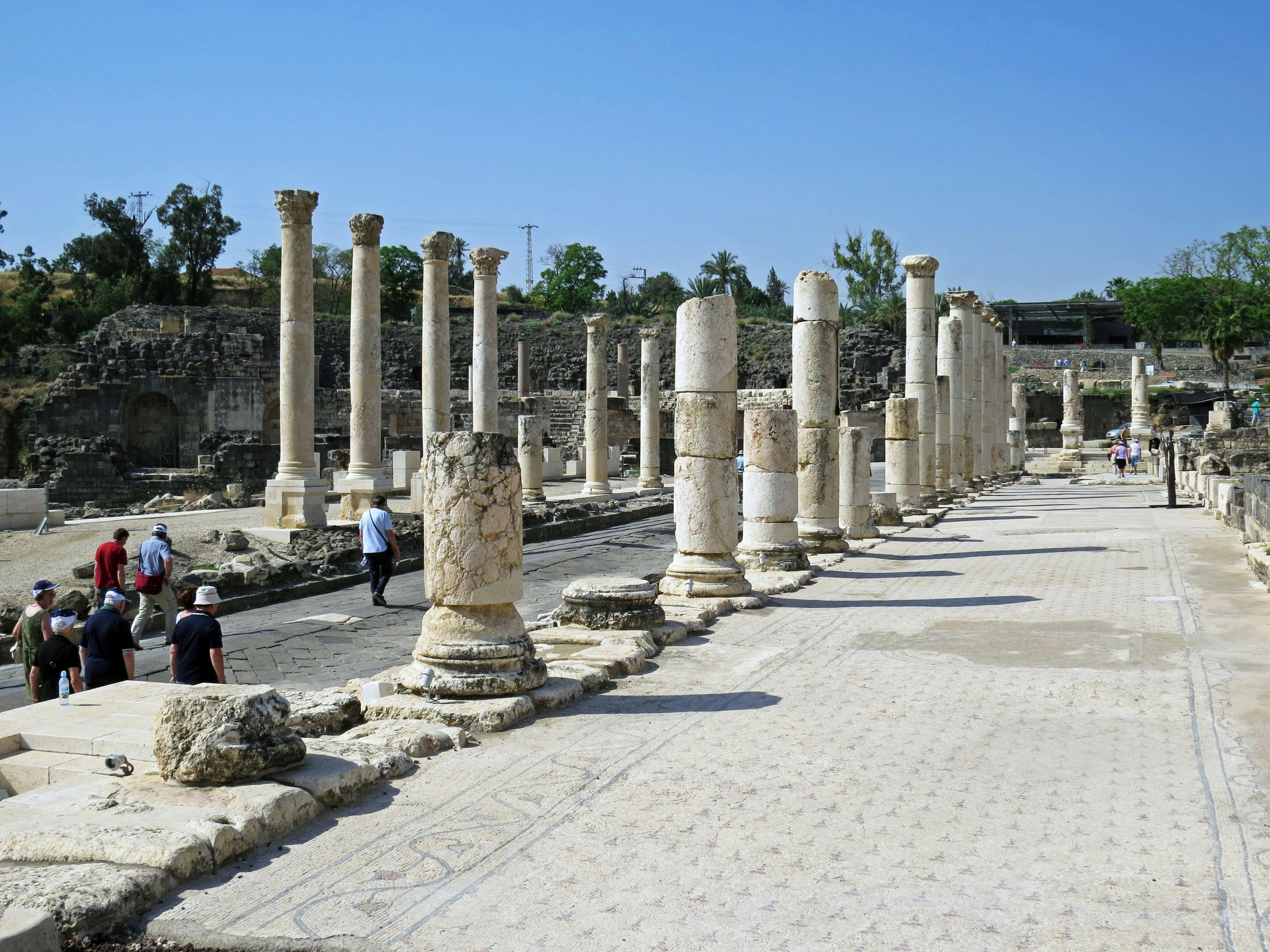 Ruines anciennes avec des colonnes bordant un chemin et des touristes