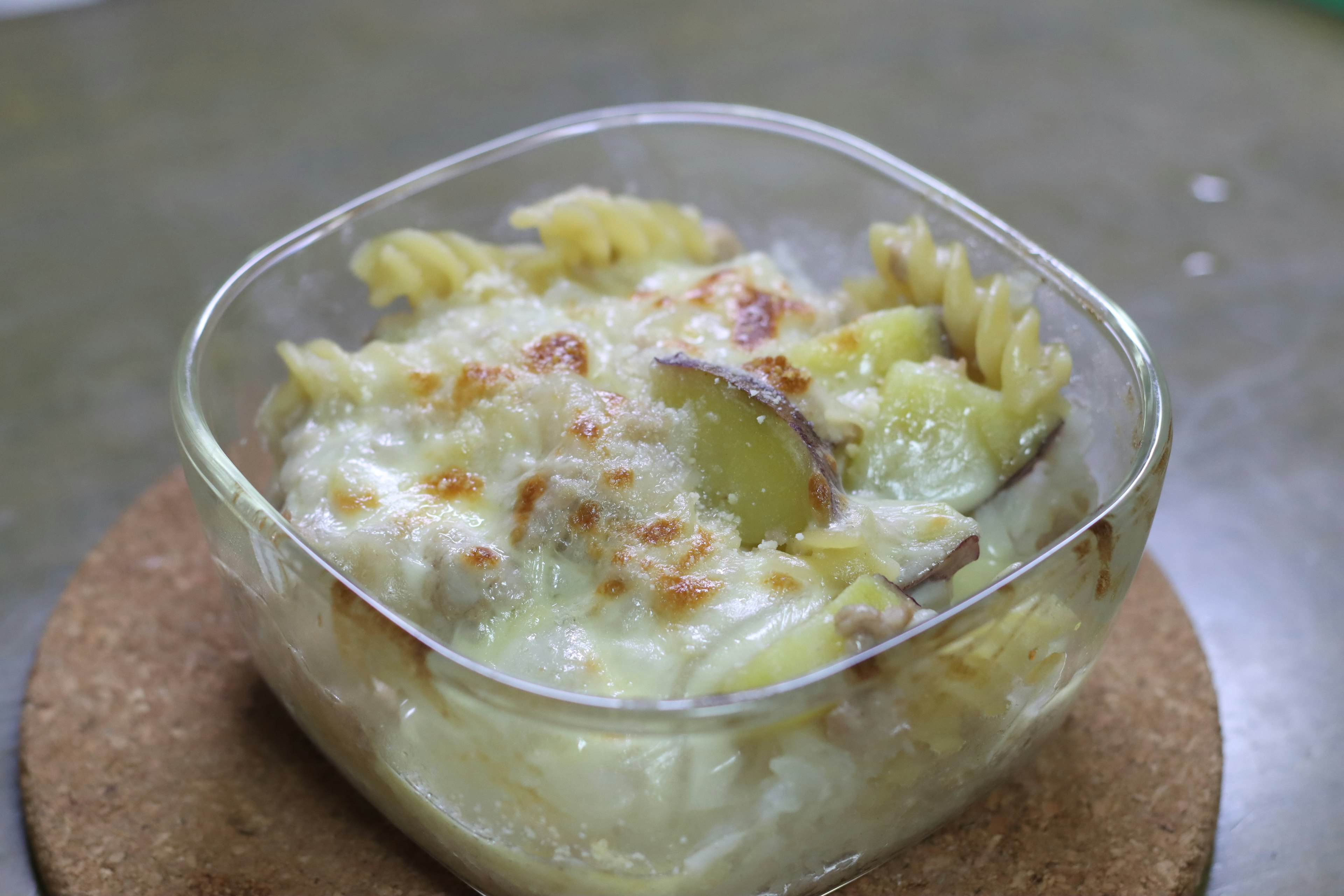 Creamy pasta and potato gratin in a transparent glass dish