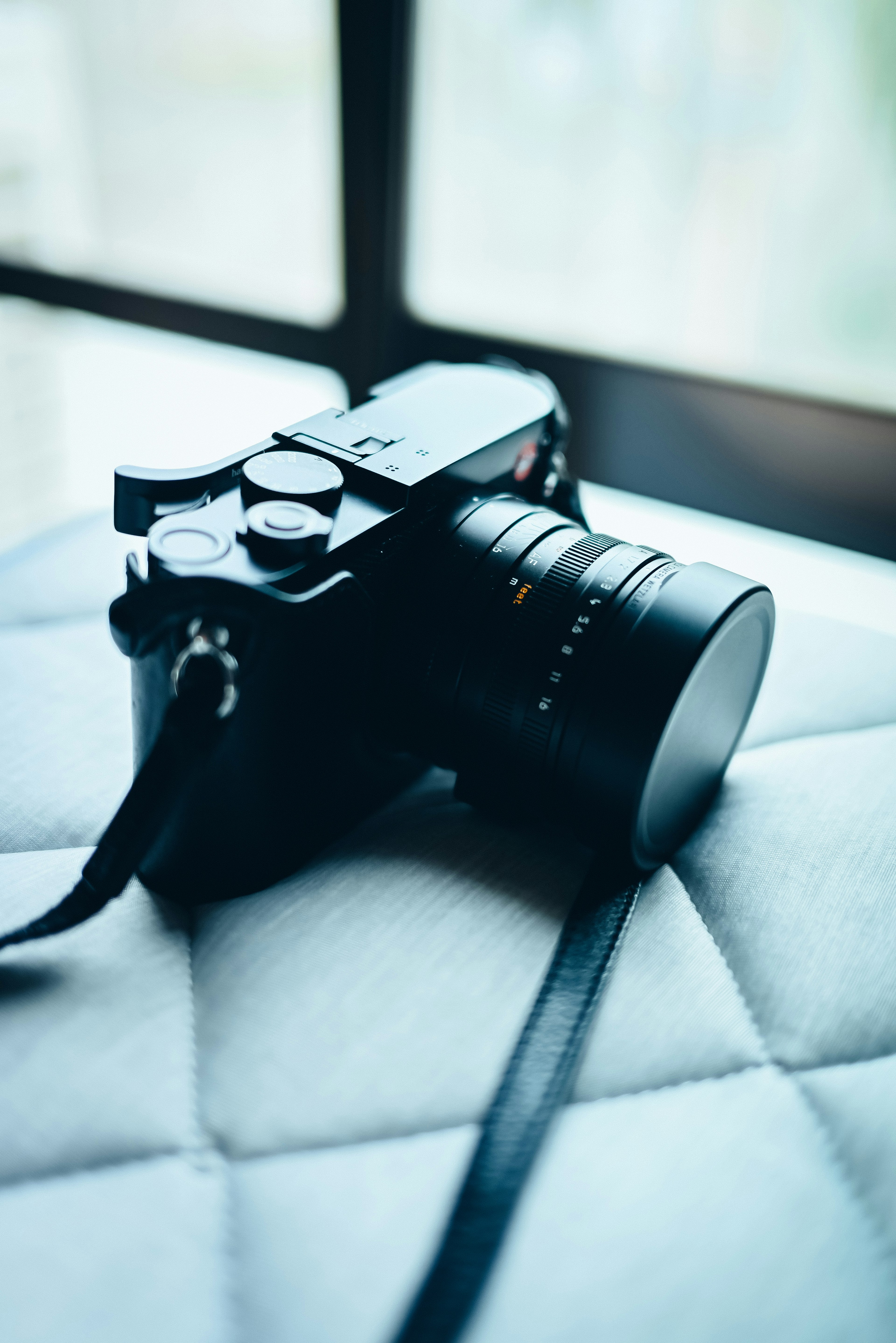 Black camera resting on a cushion near a window