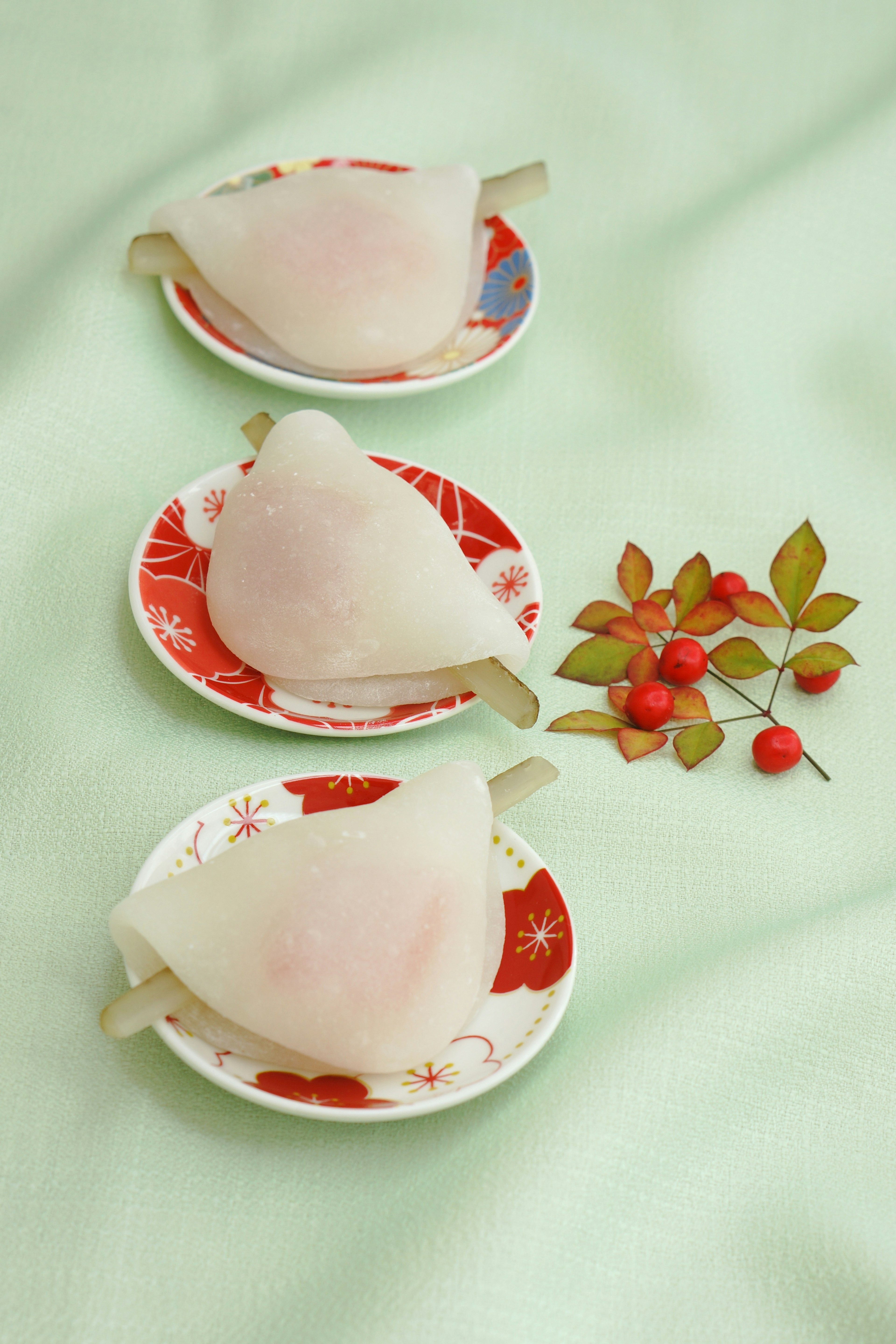 Three white dessert dumplings on decorative plates with green background