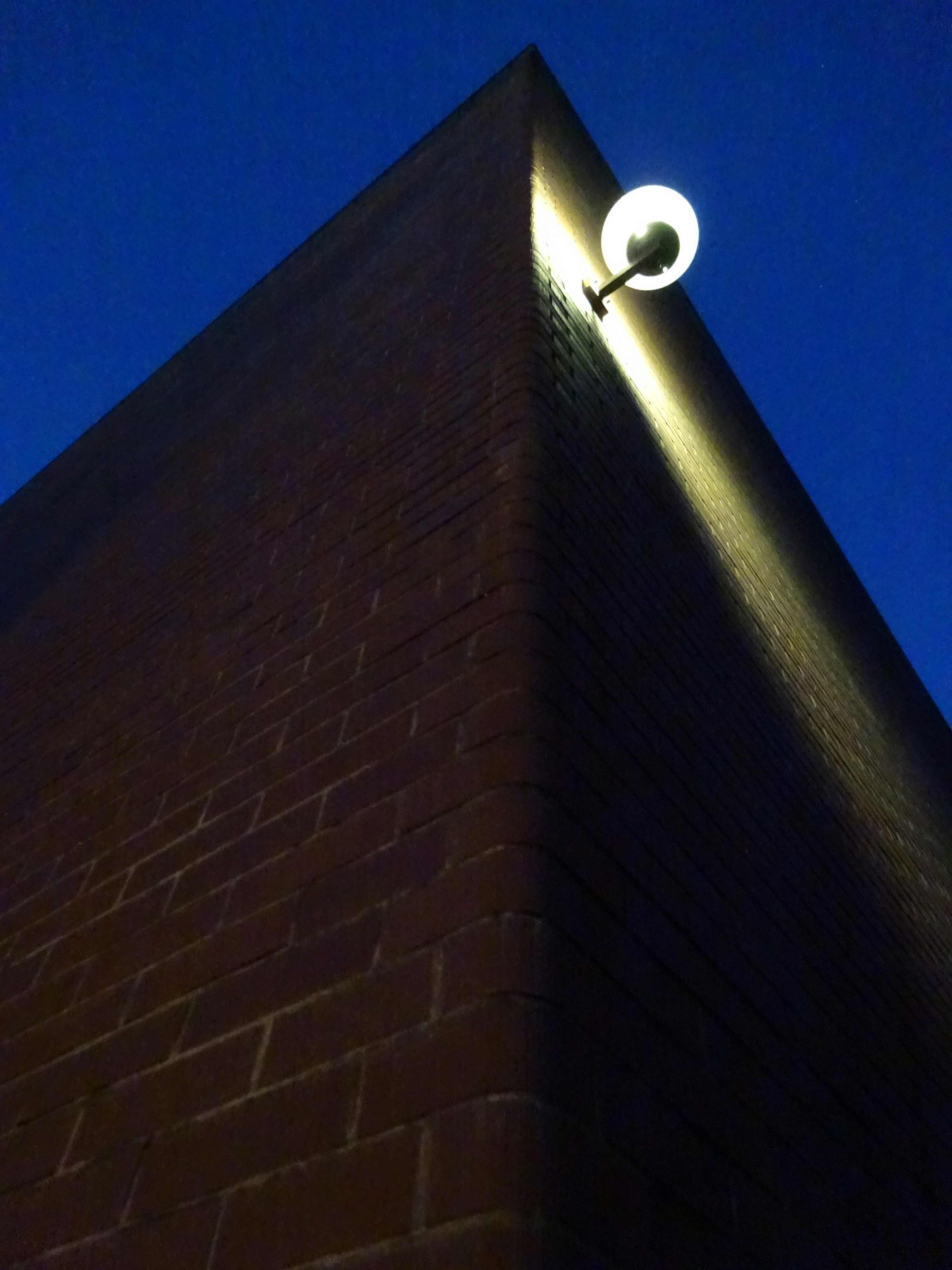 Un accesorio de luz redondo montado en la esquina de un edificio bajo un cielo azul oscuro