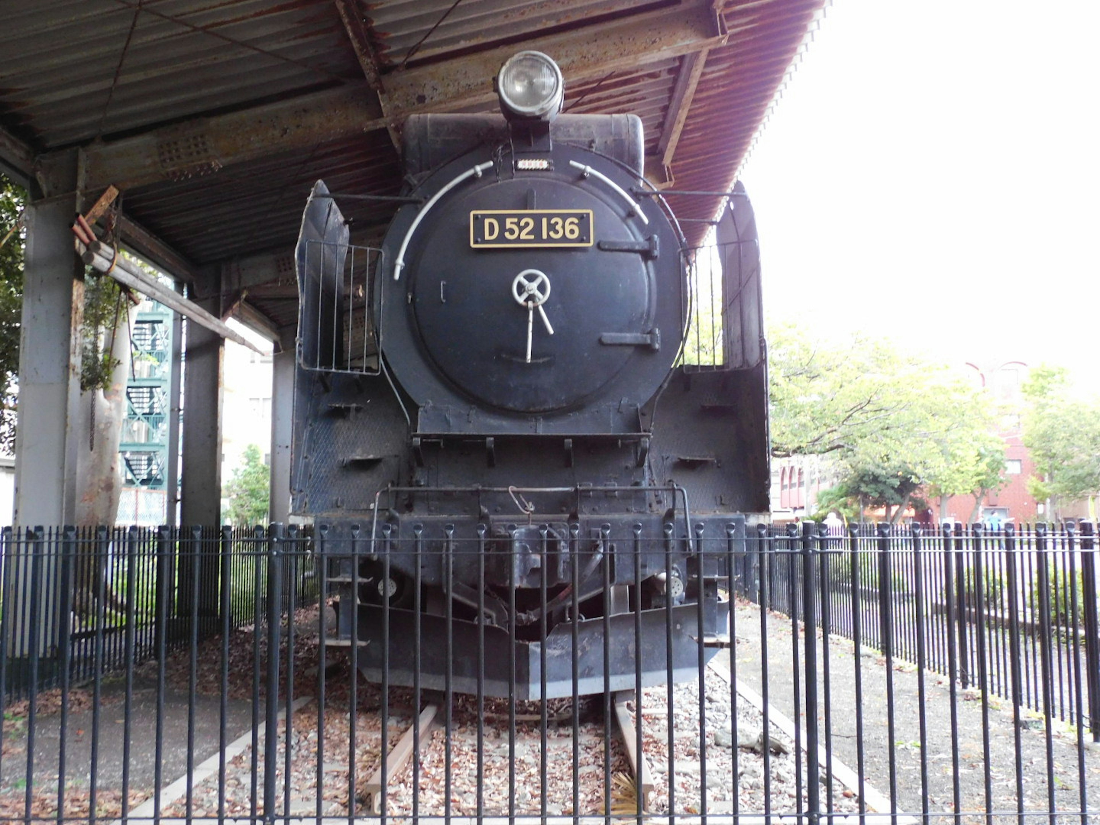 Locomotora de vapor negra en exhibición rodeada por una cerca de metal