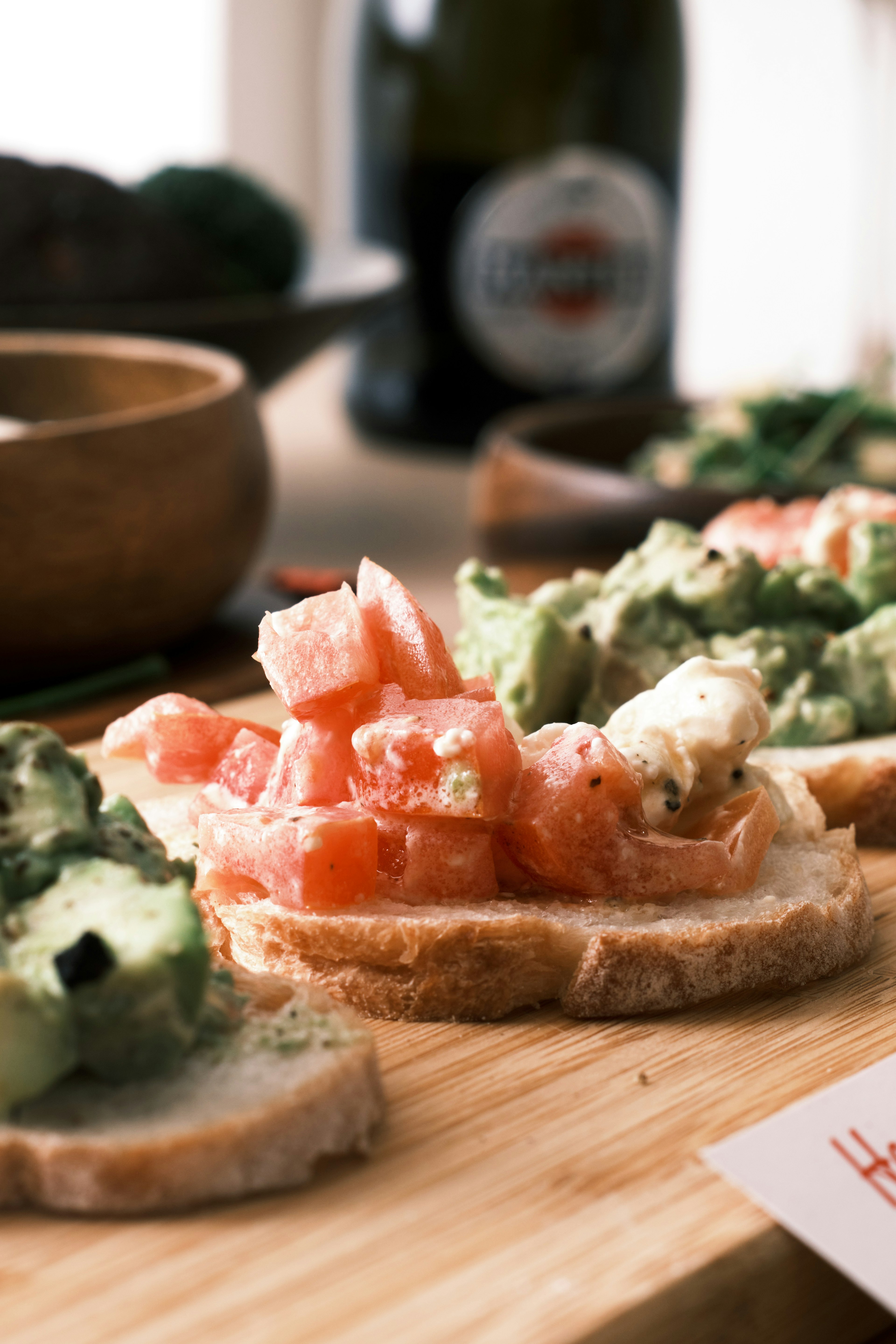 Fresh tomato and avocado toasts arranged on a wooden board