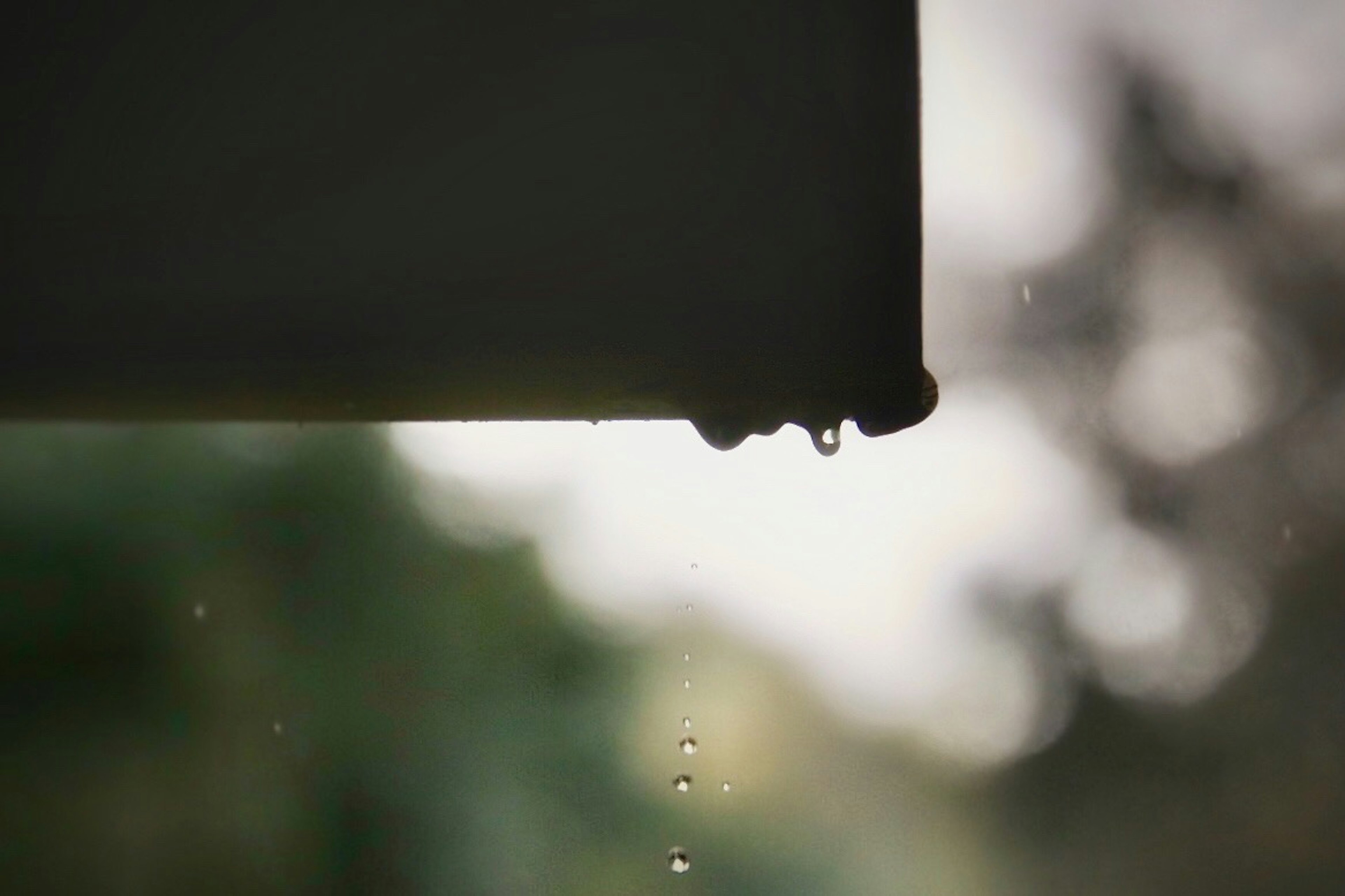 Nahaufnahme der Dachkante mit tropfendem Regenwasser