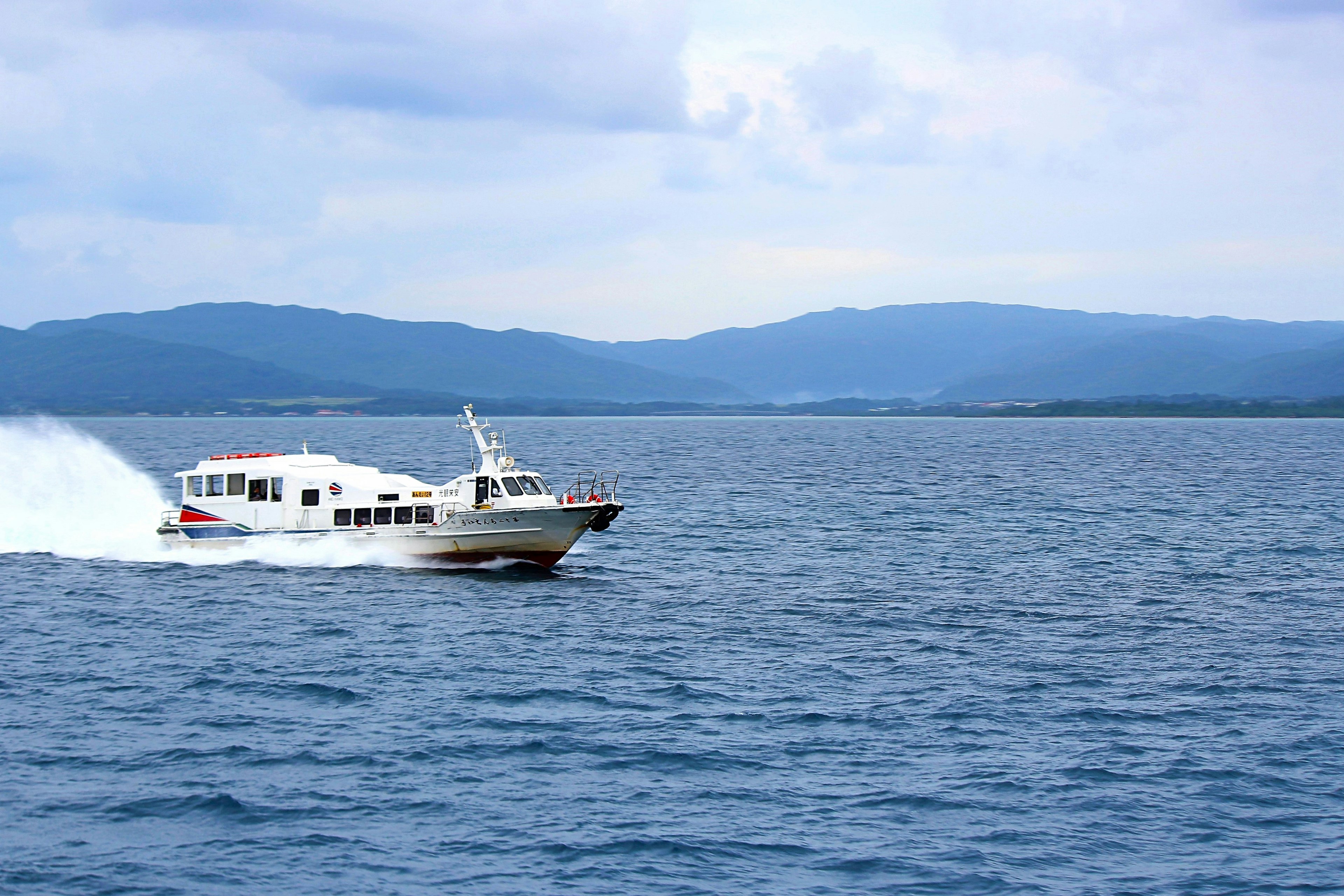 Un barco acelerando sobre aguas azules con montañas al fondo