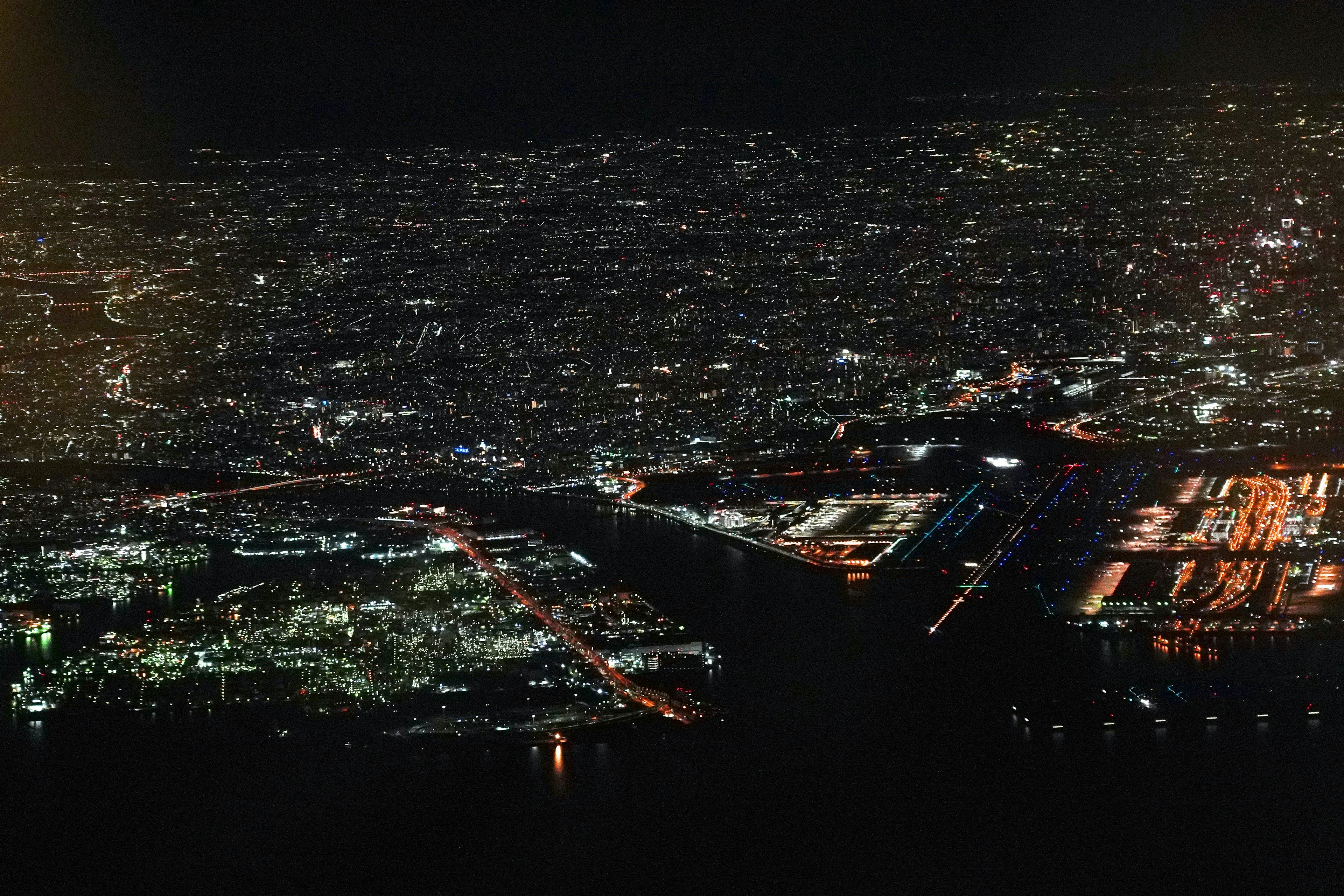 Aerial view of a city at night with bright streetlights illuminating a vast area