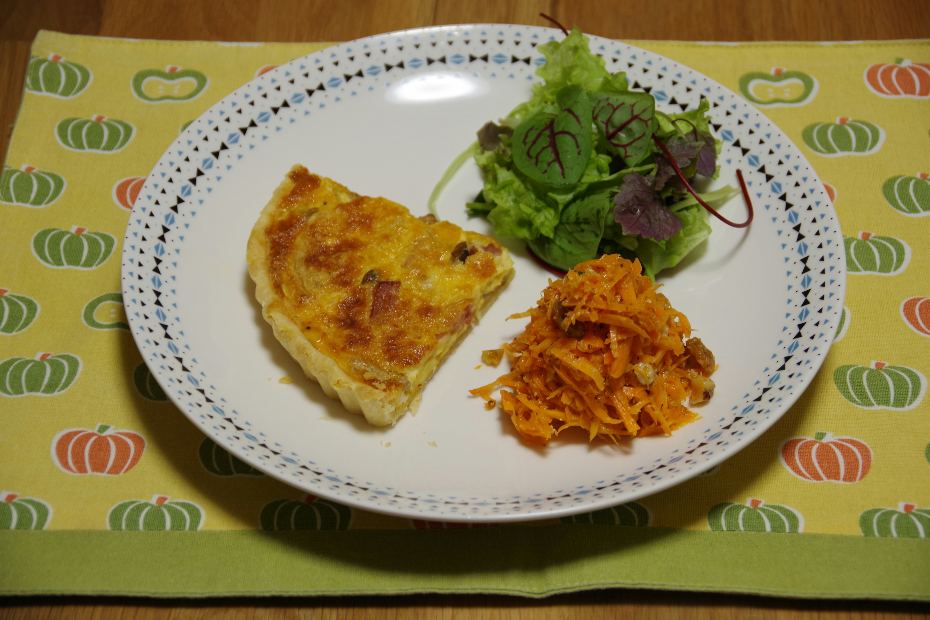 Un plato con una porción de frittata junto a una ensalada verde y ensalada de zanahoria rallada