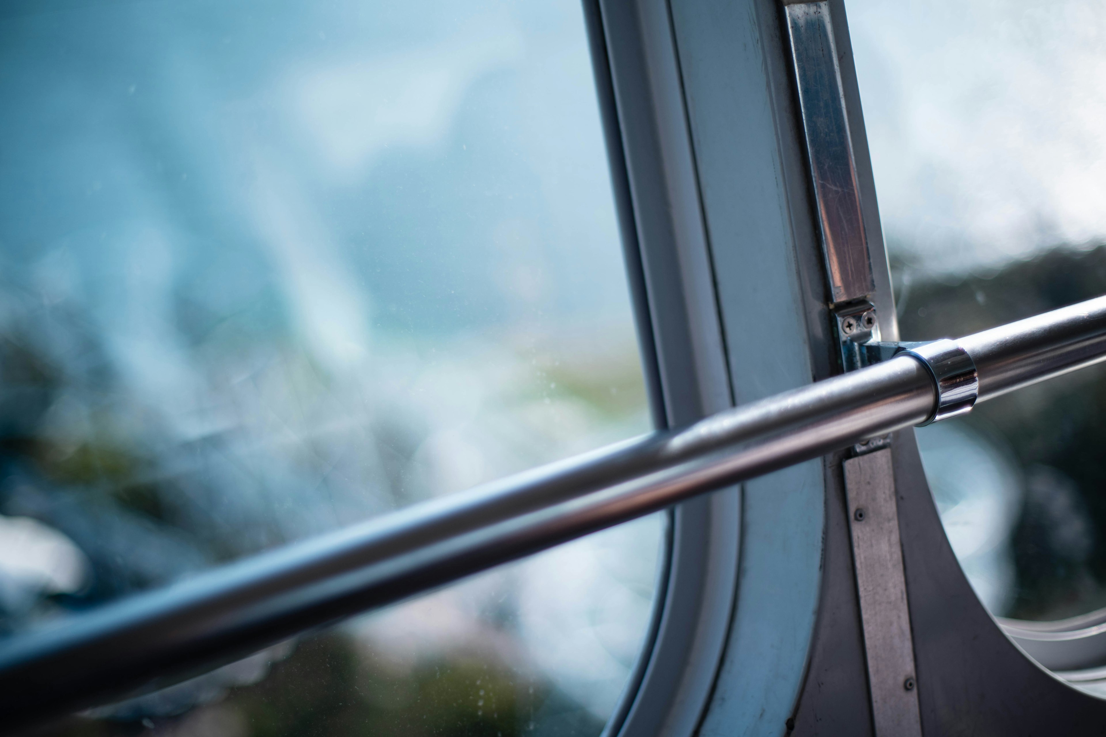 Pasamanos de metal cerca de una ventana con un paisaje borroso