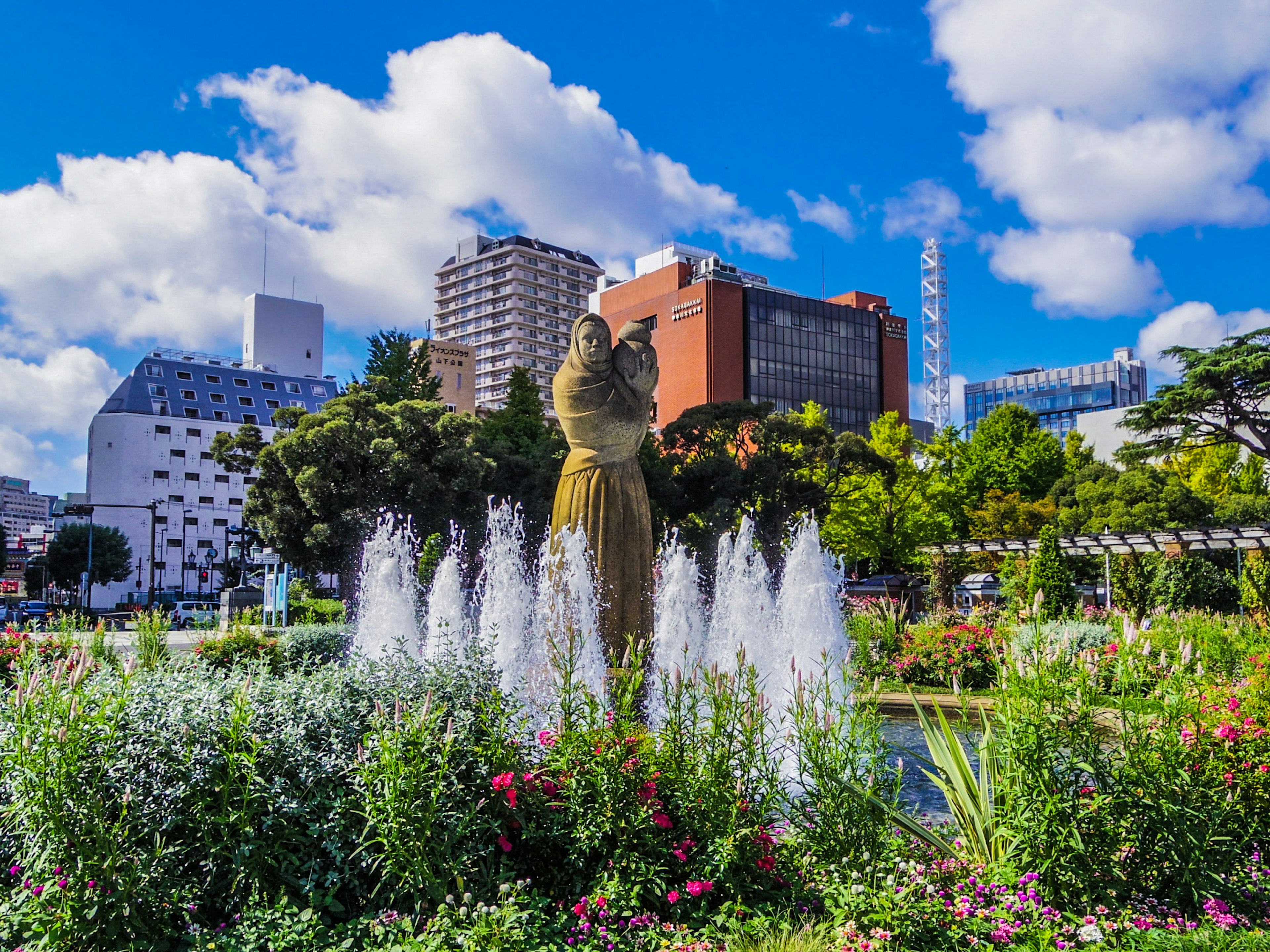 Vista panoramica di un parco con fontana e fiori colorati grattacieli sullo sfondo