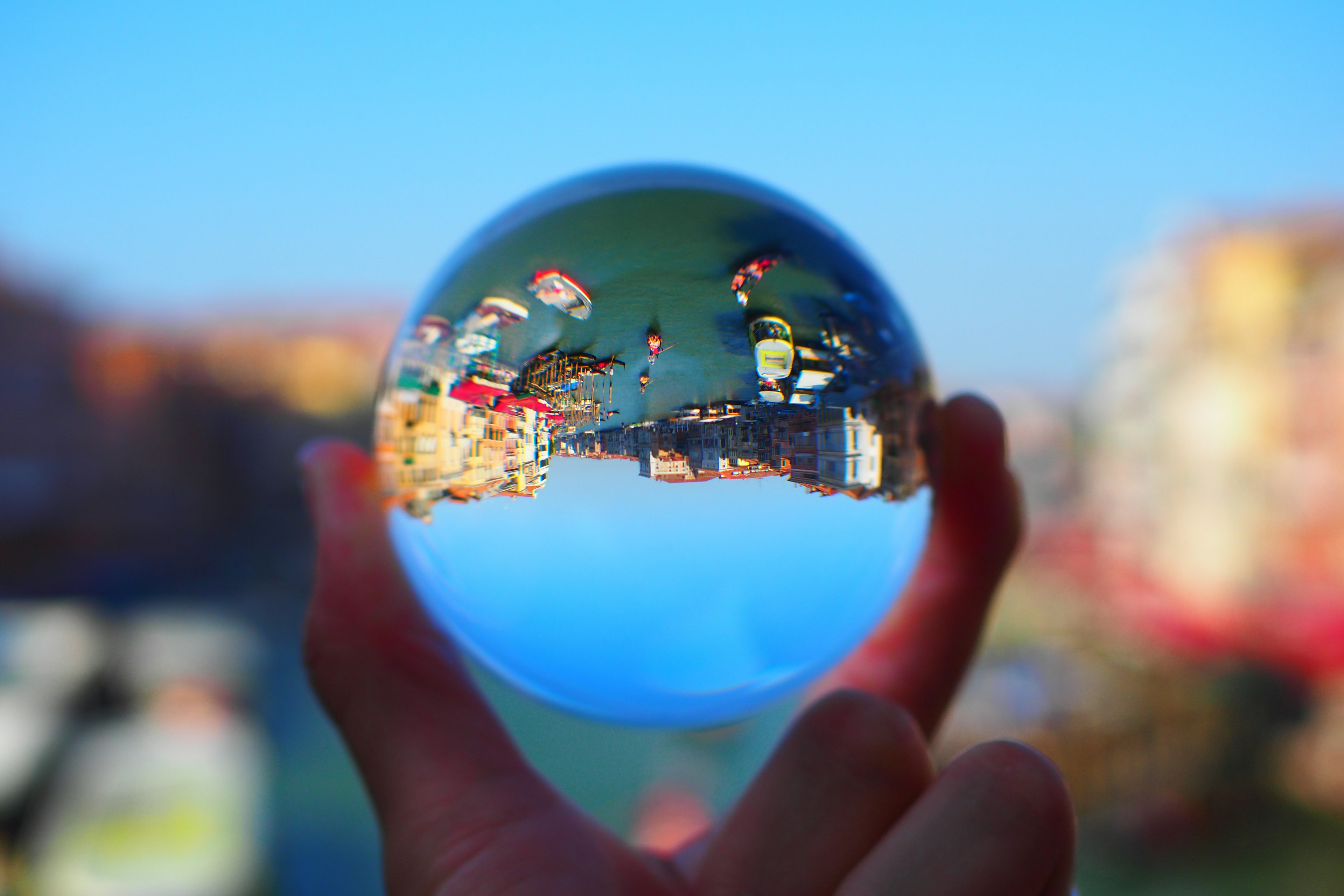 Mano che tiene una sfera di cristallo che riflette un paesaggio urbano vivace