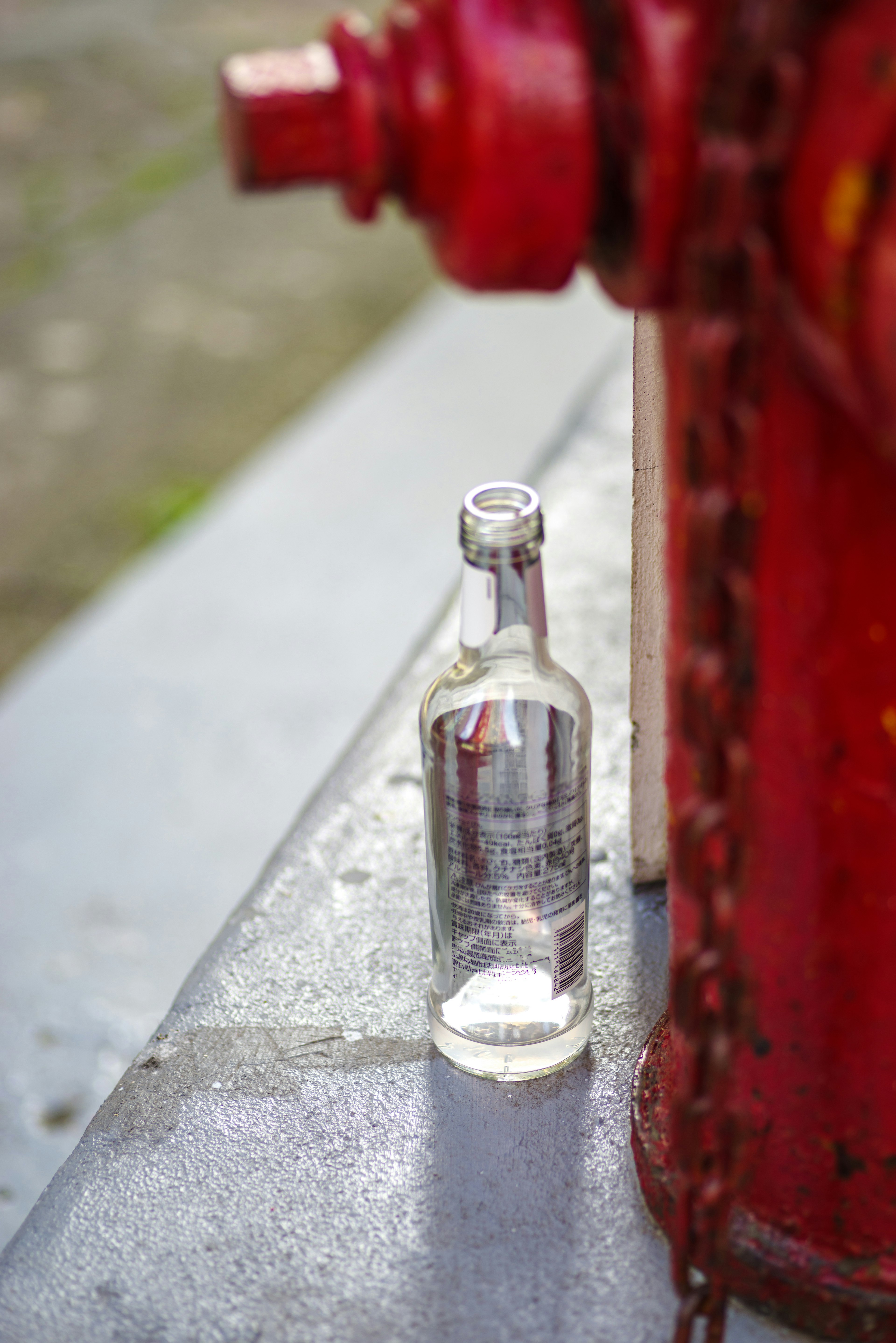 Eine klare Glasflasche neben einem roten Hydranten