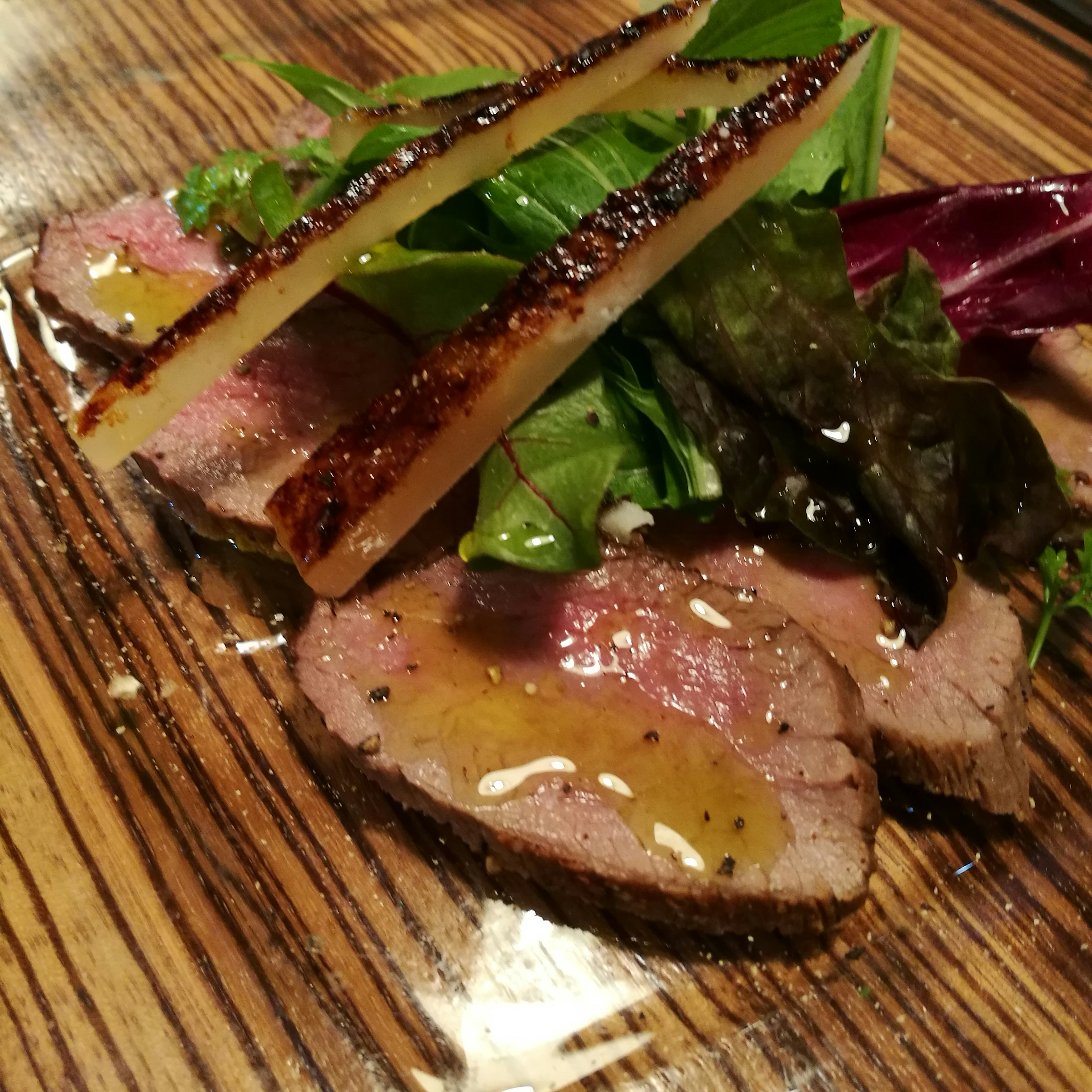 Carne en rodajas presentada de manera hermosa con verduras frescas y salsa