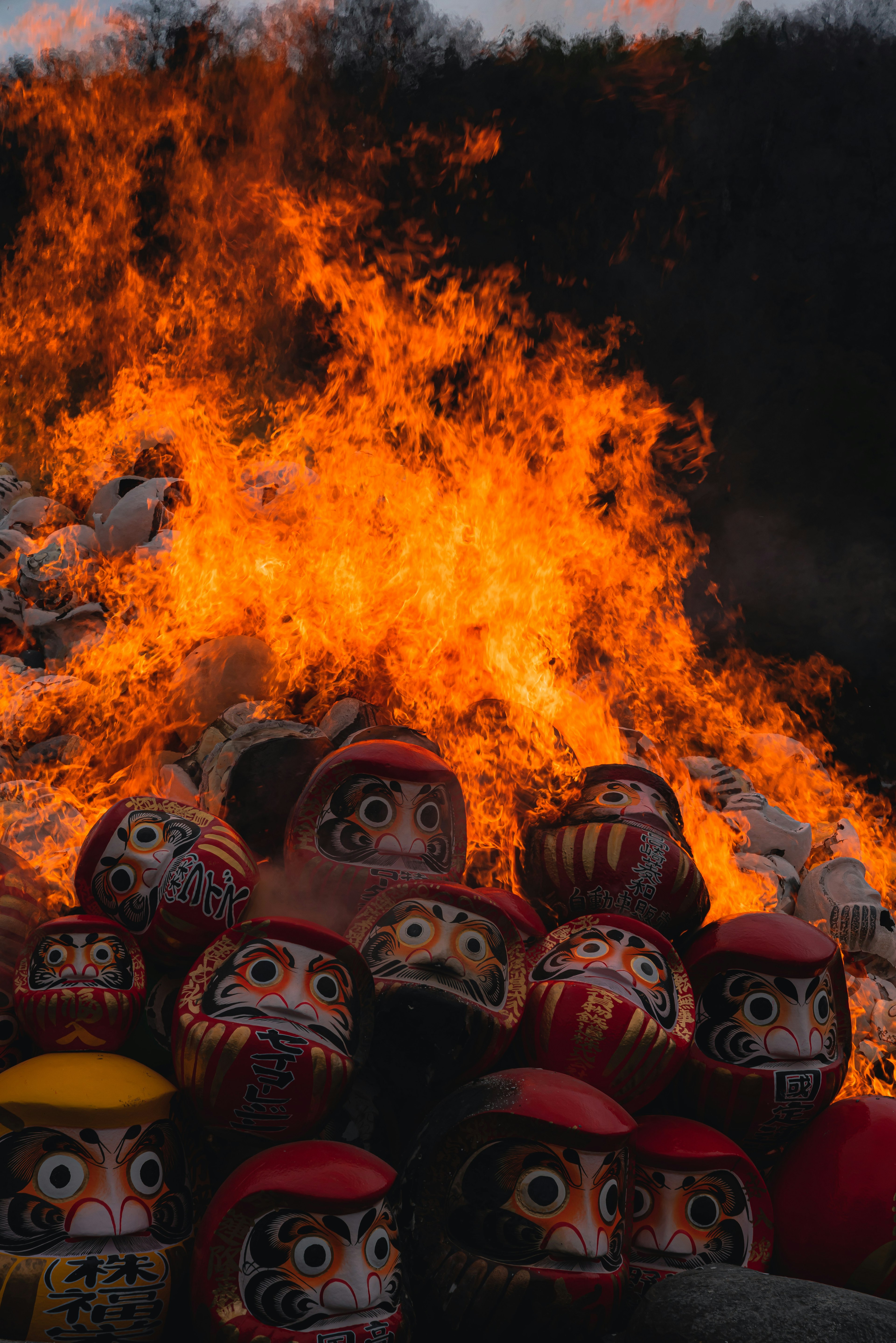 Muñecas Daruma apiladas frente a un gran fuego