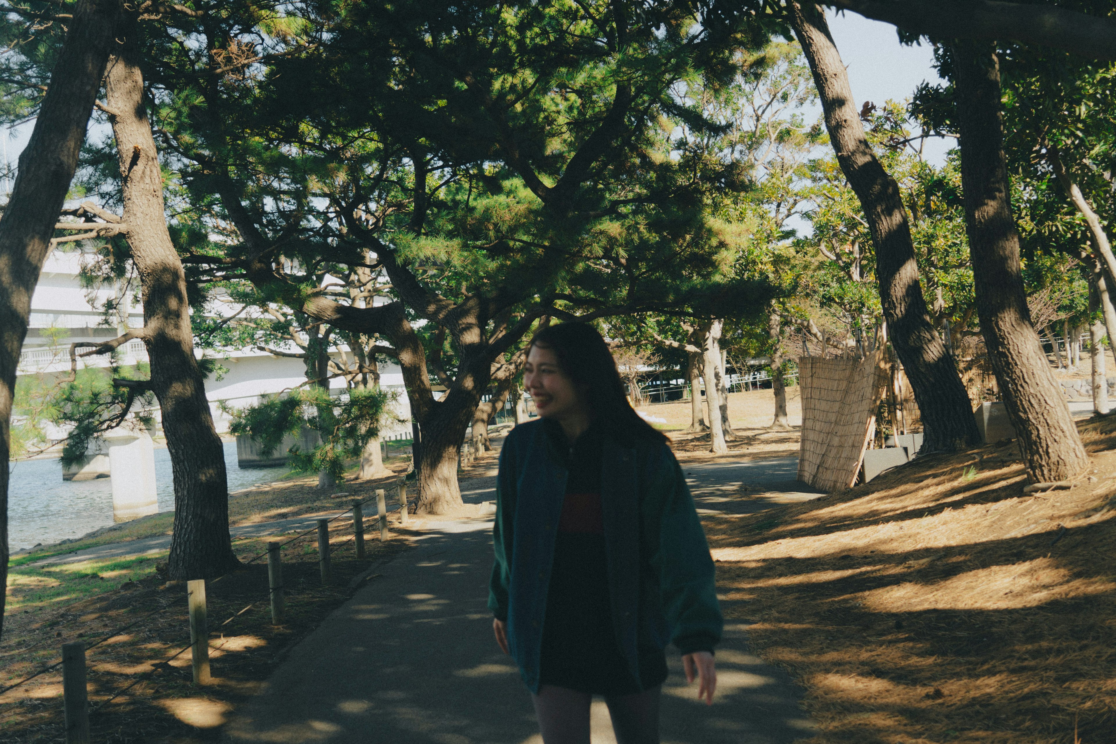 公園の小道を歩く女性 緑の木々に囲まれた穏やかな風景