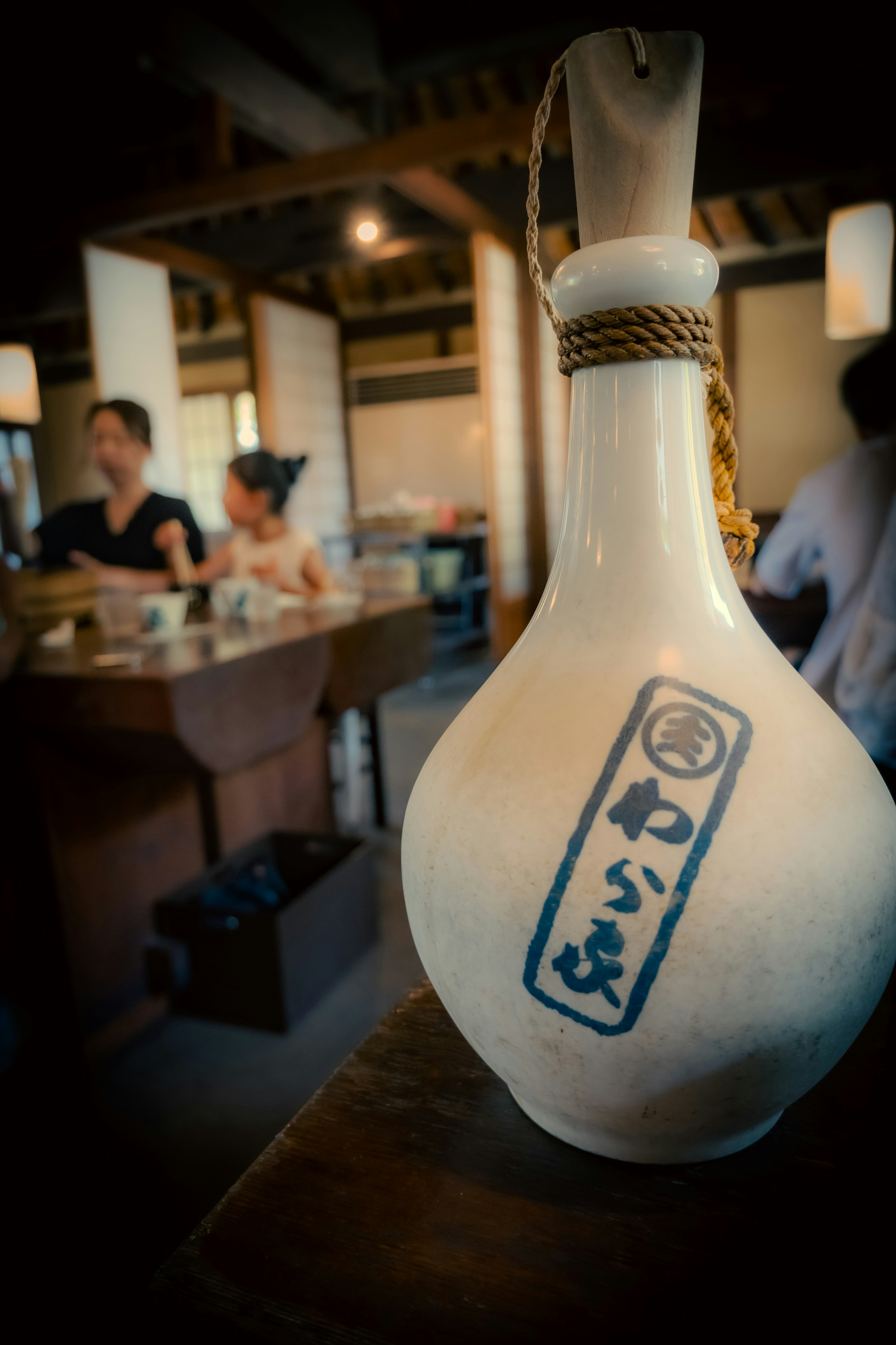 Bouteille de sake blanche avec inscription bleue dans un bar japonais