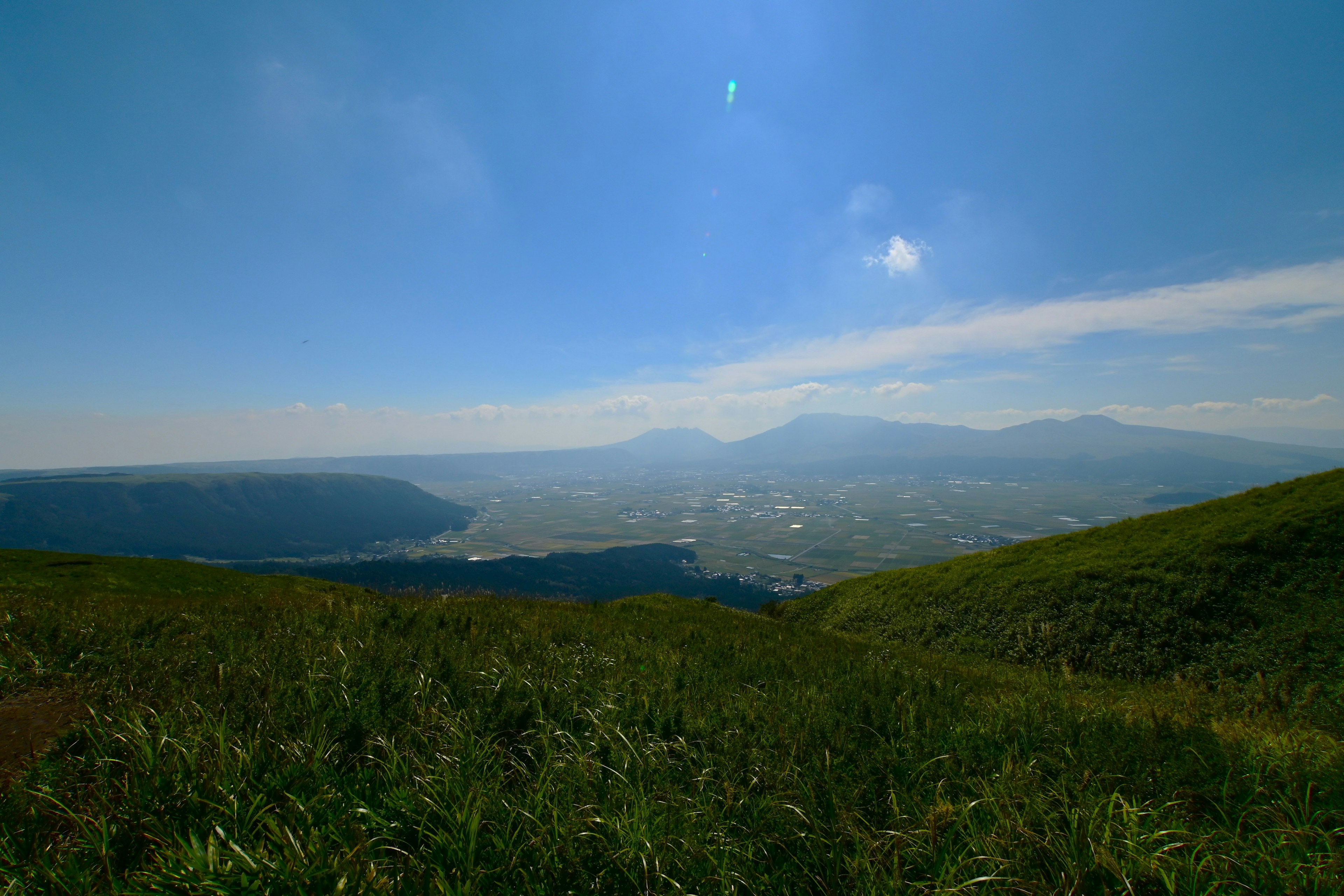 青空と緑の草原から見える山の風景