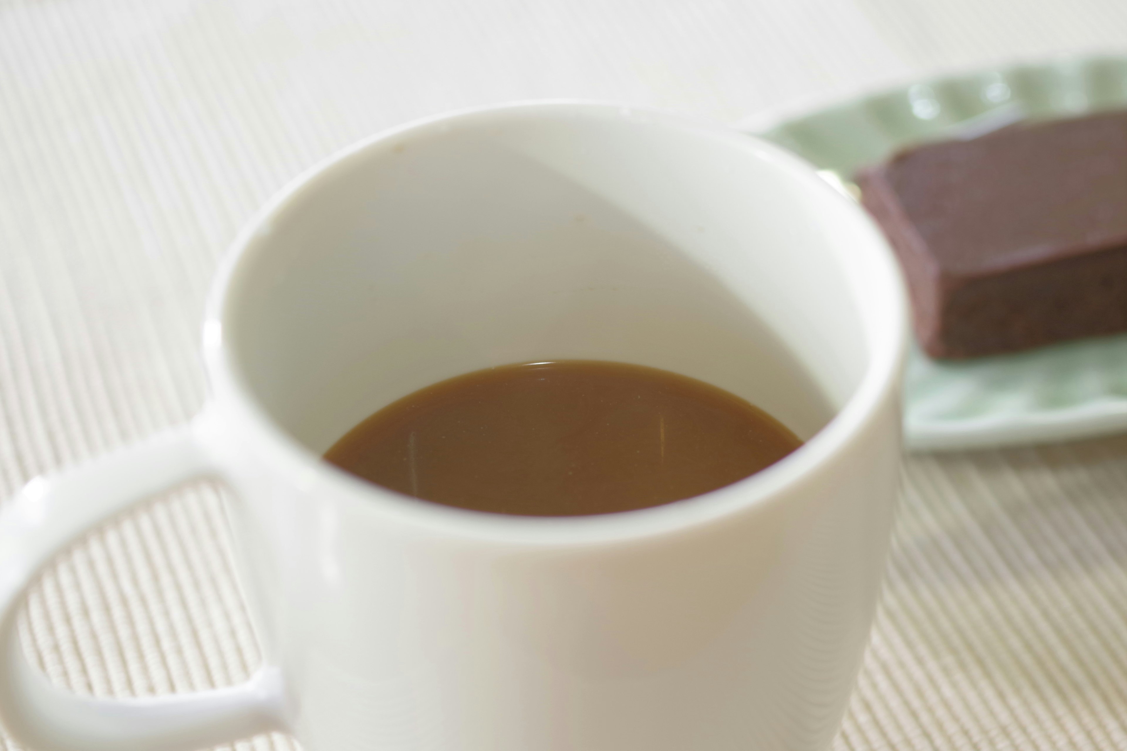 Kaffee in einer weißen Tasse mit Schokolade auf einem grünen Teller