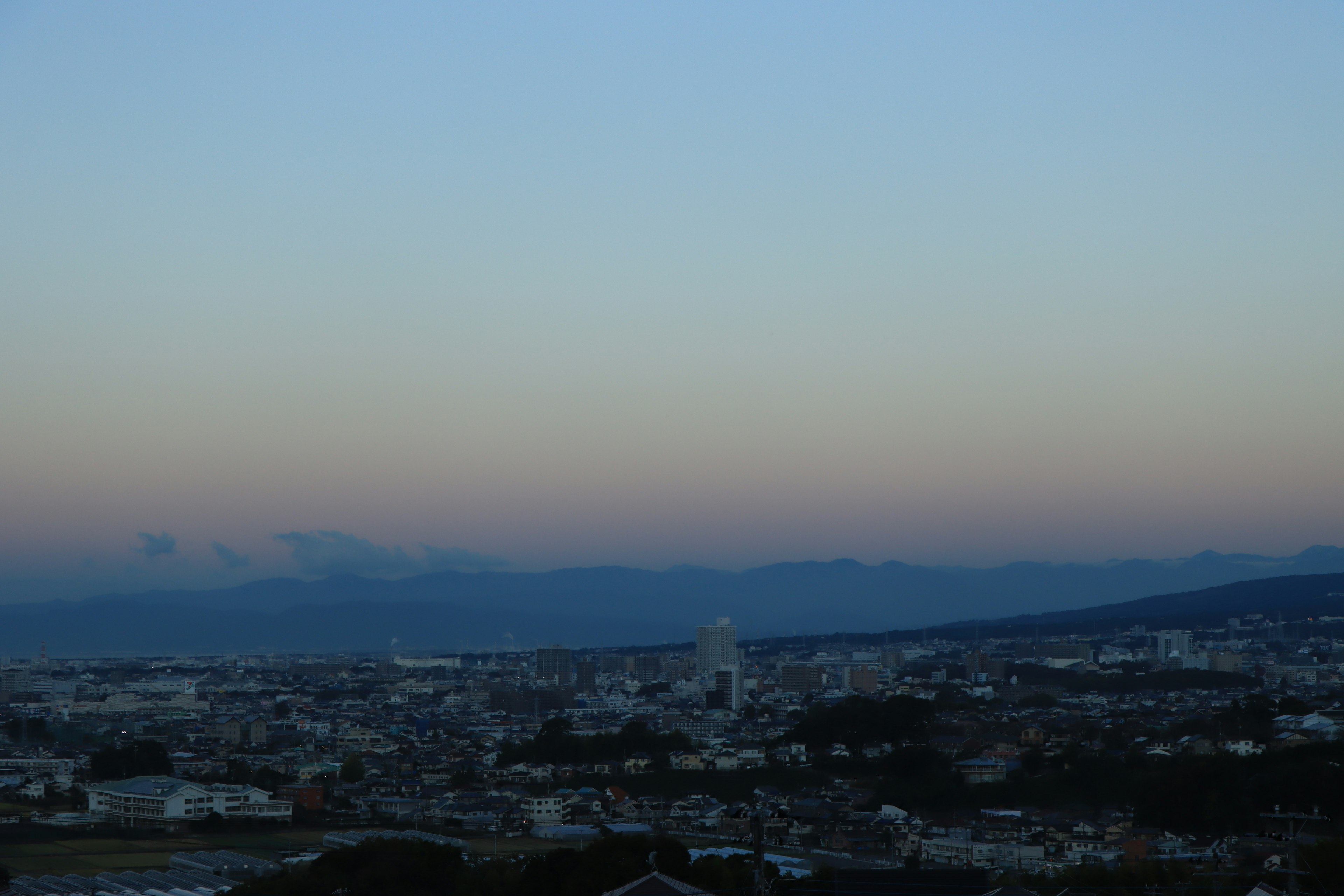 Paisaje urbano al atardecer con montañas al fondo