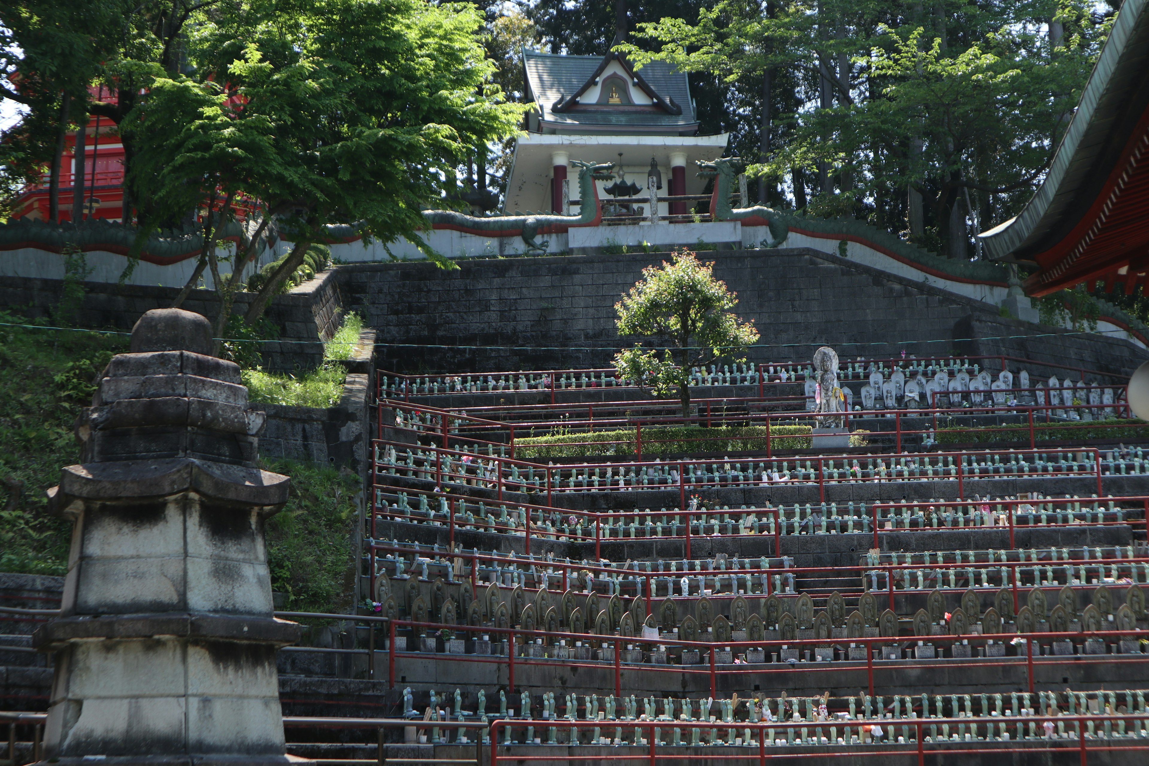 階段状の石の壁と緑豊かな木々の背景にある寺院