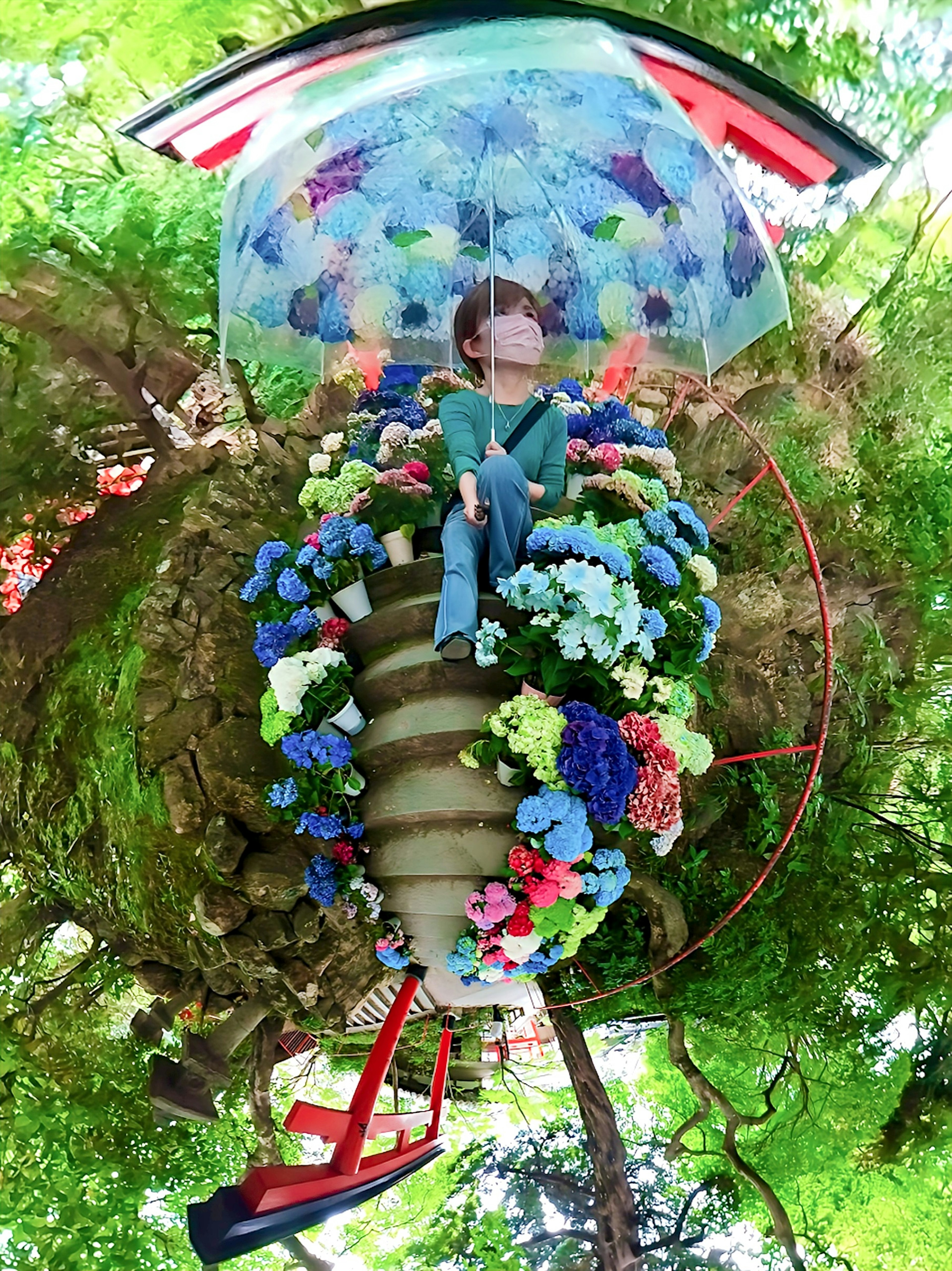 Une personne assise sous un parapluie coloré entourée de fleurs dans un cadre féerique