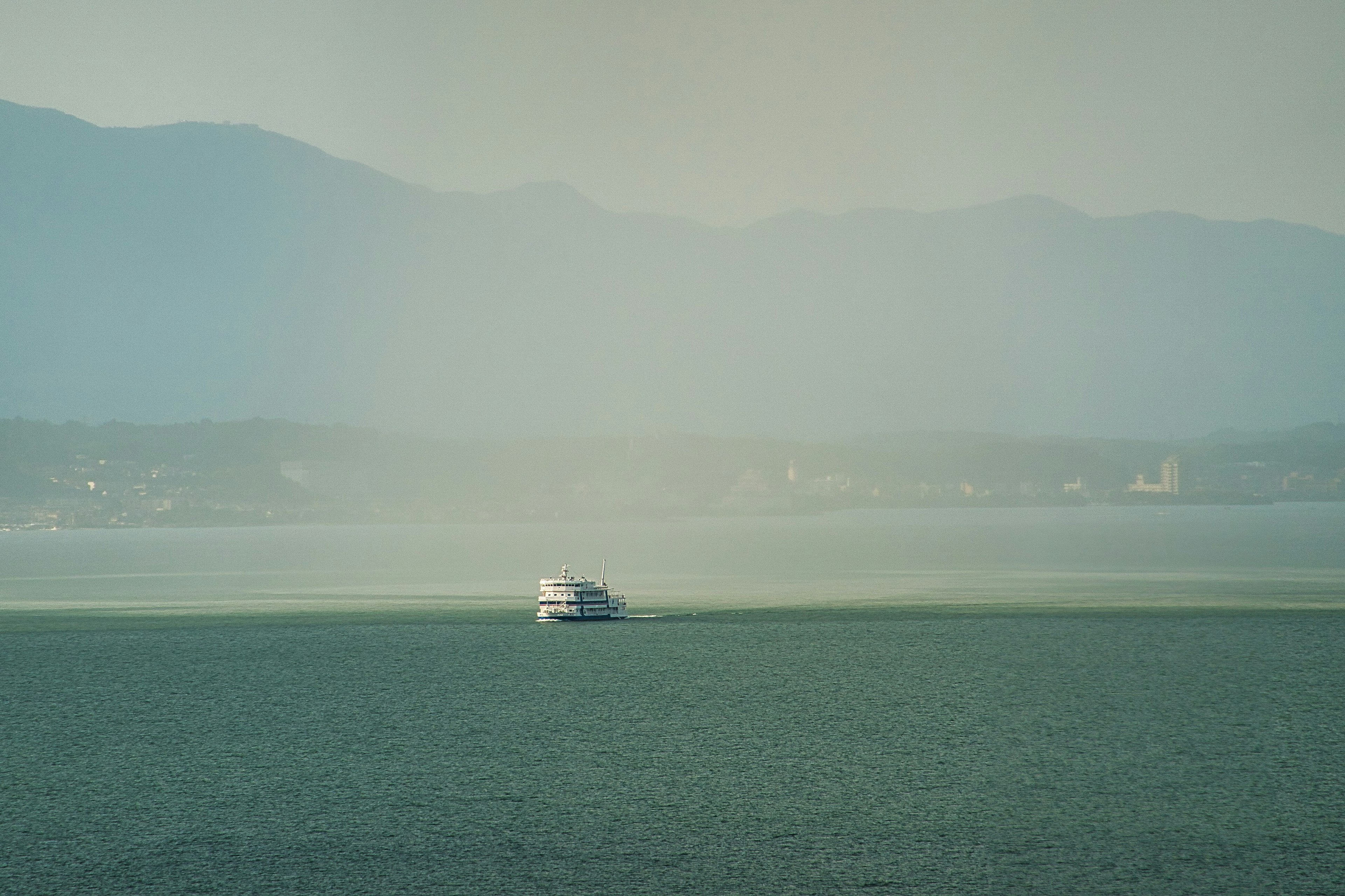 A boat sailing on a calm sea with mountains in the background