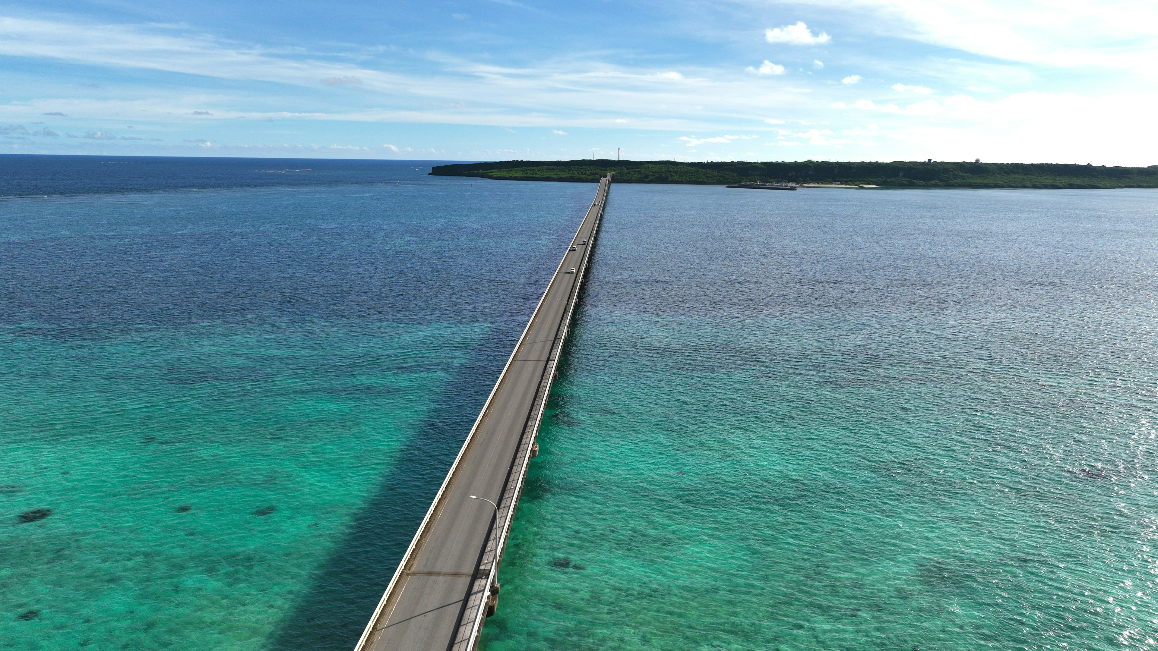 Eine lange Brücke, die über türkisfarbenes Wasser unter einem blauen Himmel führt