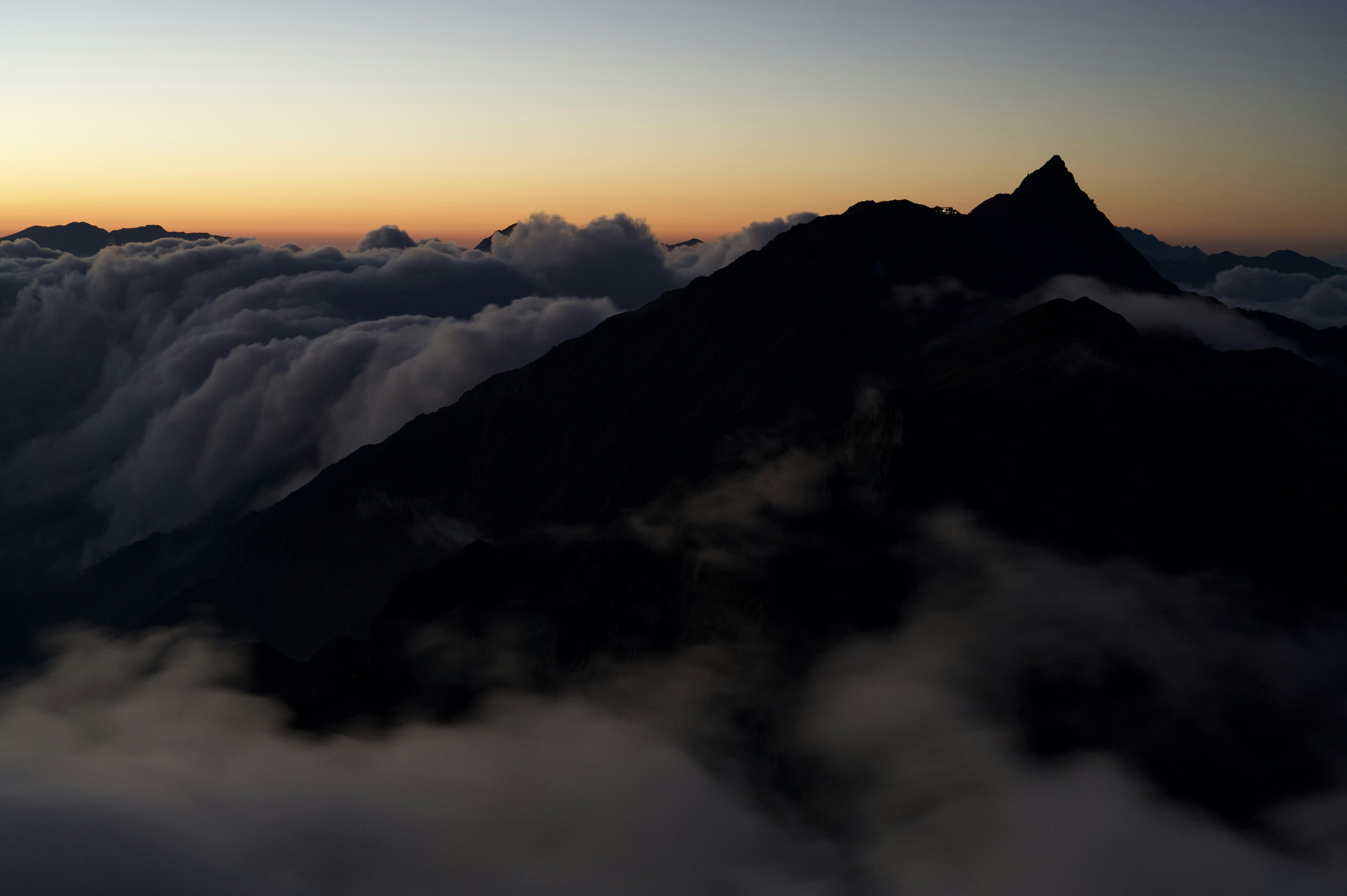 Silhouette eines Berges über den Wolken mit einem Sonnenuntergangshimmel