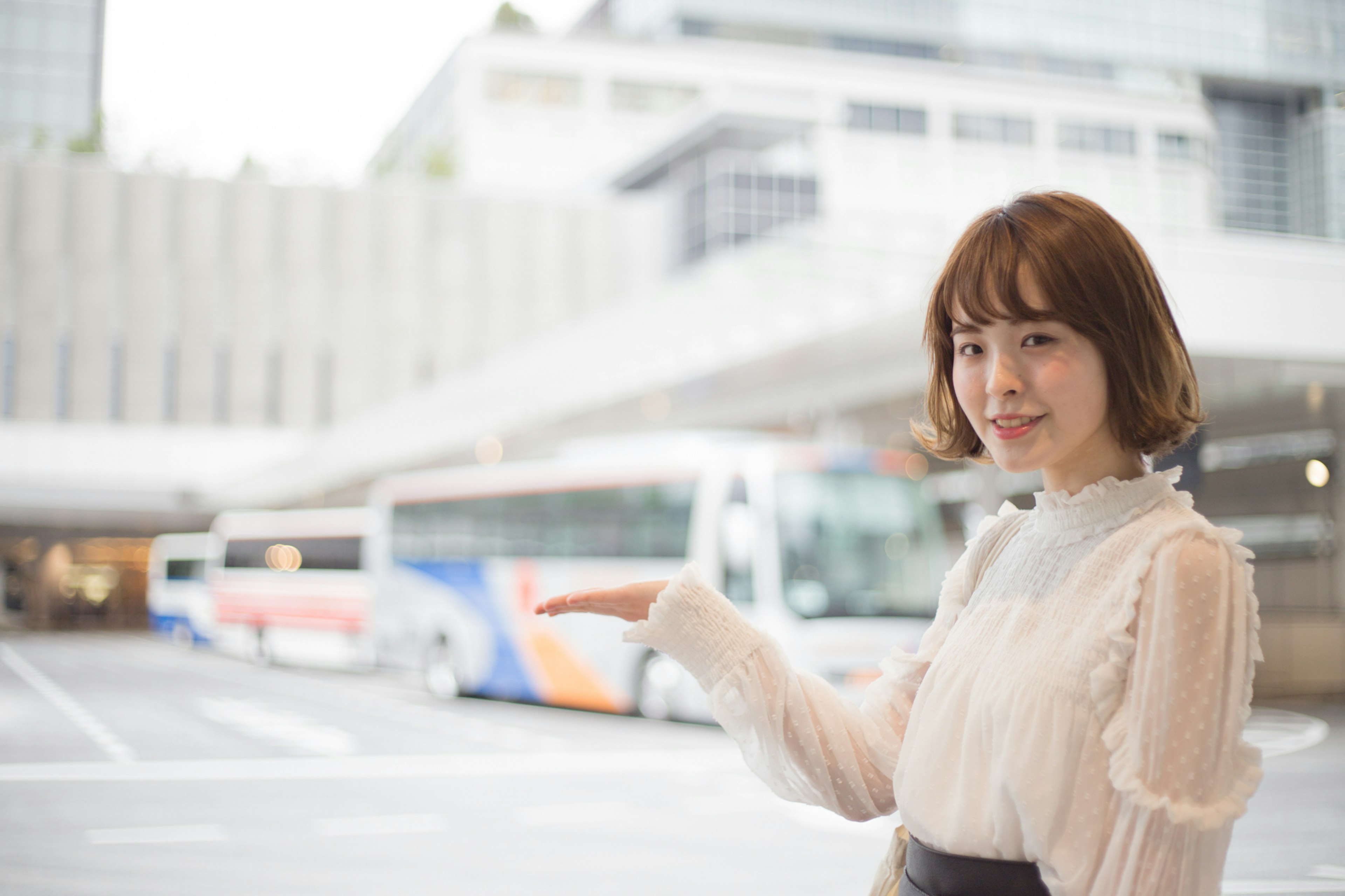 A woman pointing towards buses in a transportation hub