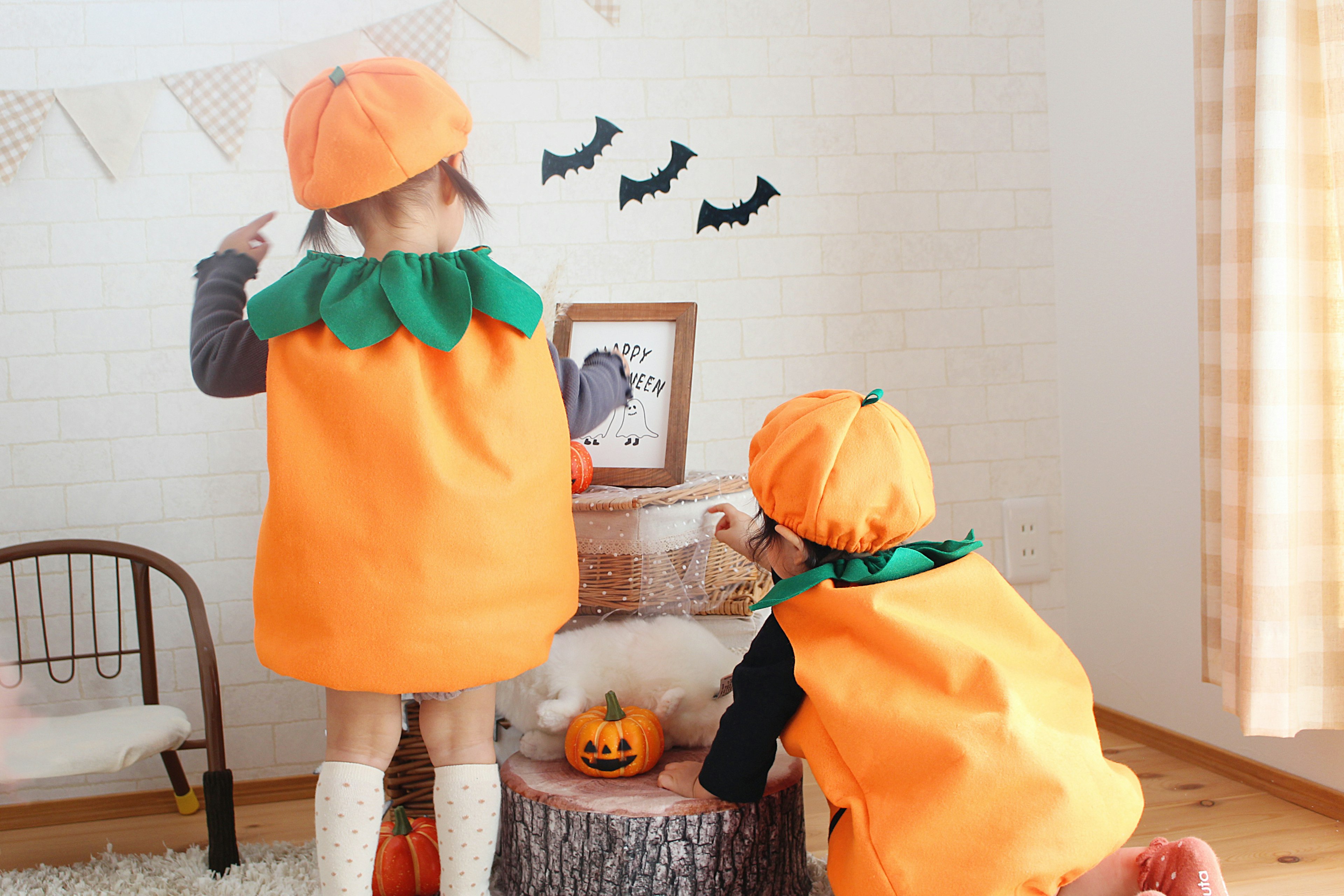 Children wearing pumpkin costumes playing indoors with Halloween decorations