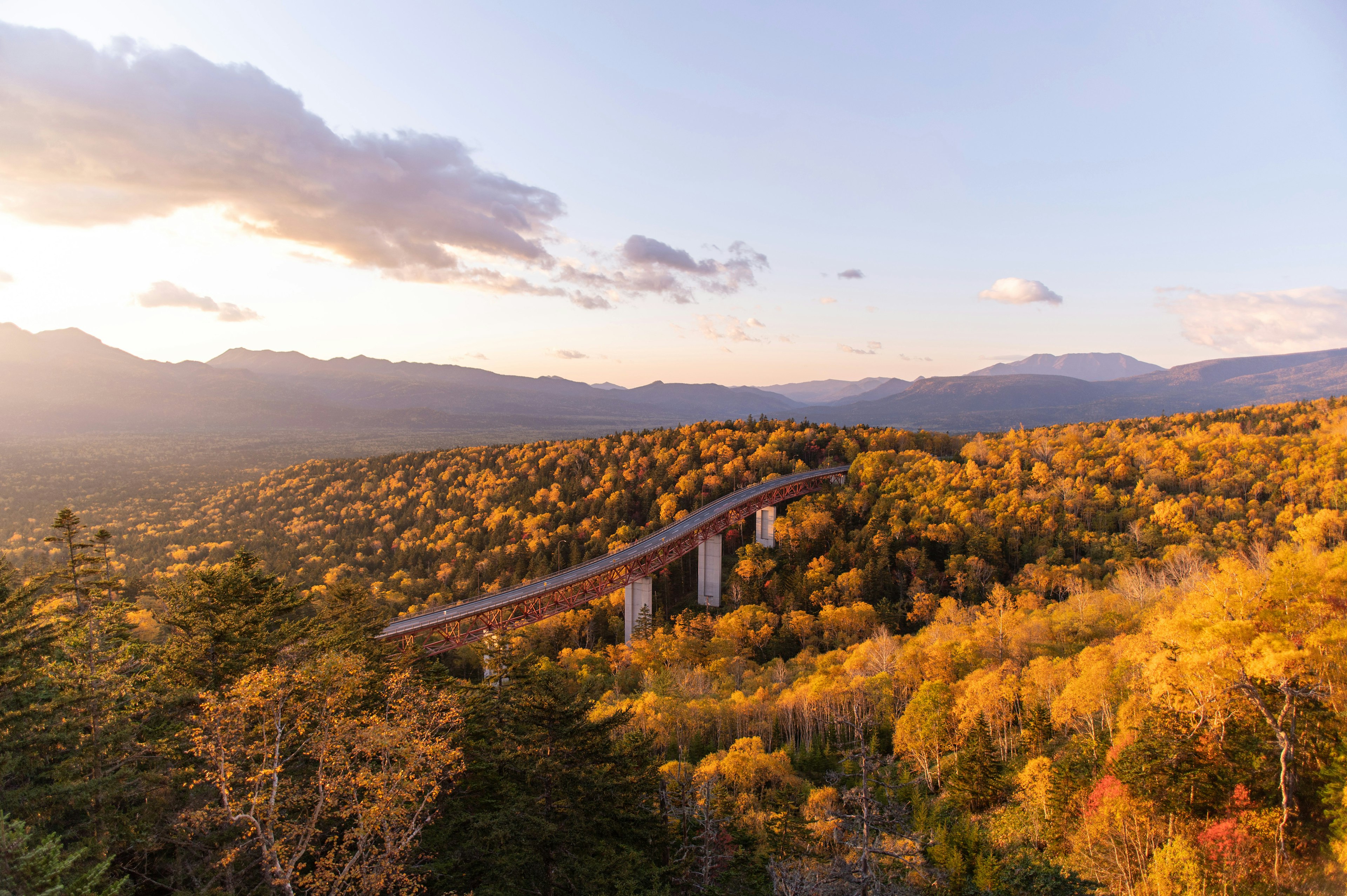 Malersicher Blick auf ein Viadukt umgeben von herbstlichem Laub und Bergen