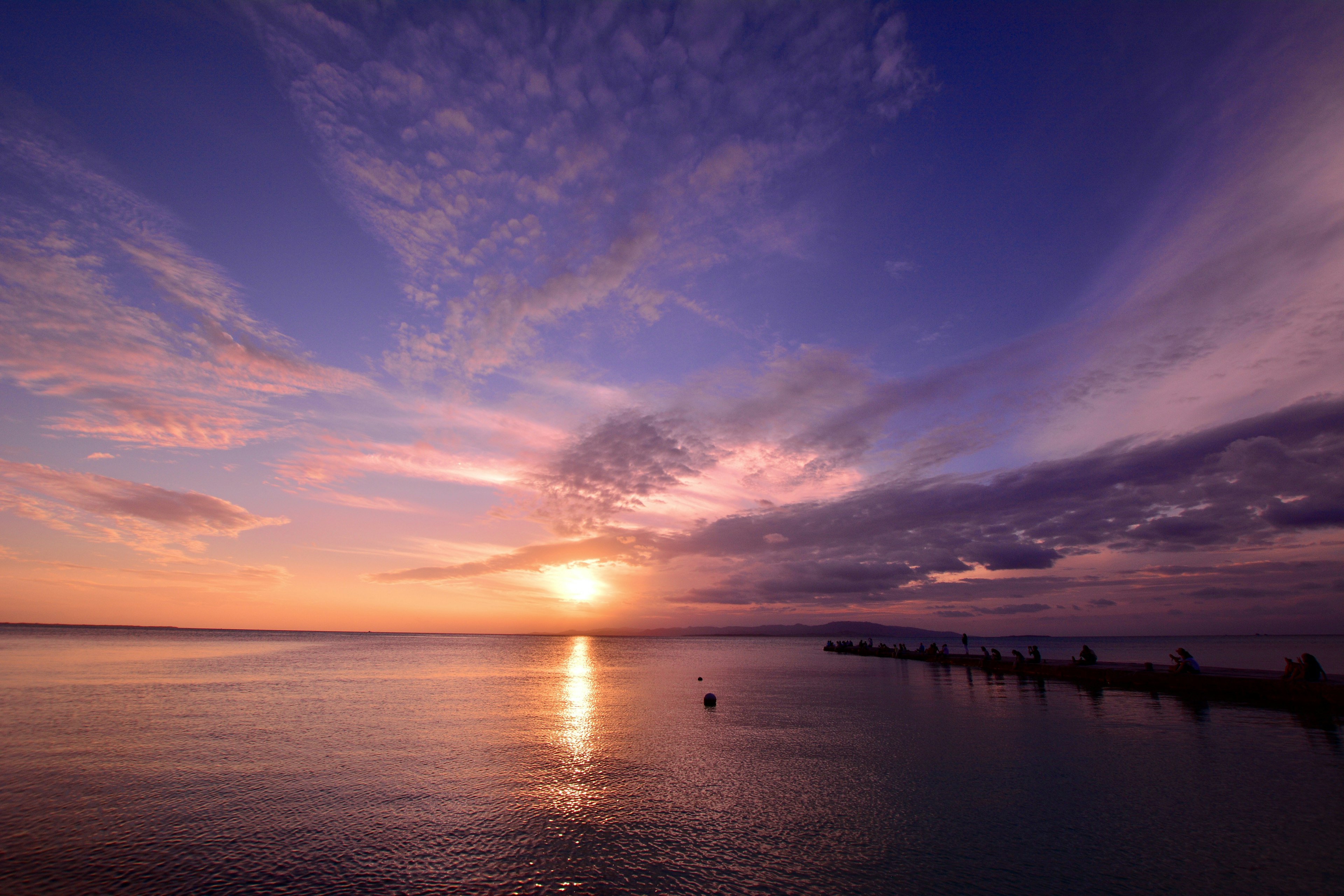 Schöner Sonnenuntergang über dem Ozean mit bunten Wolken und Reflexionen im Wasser