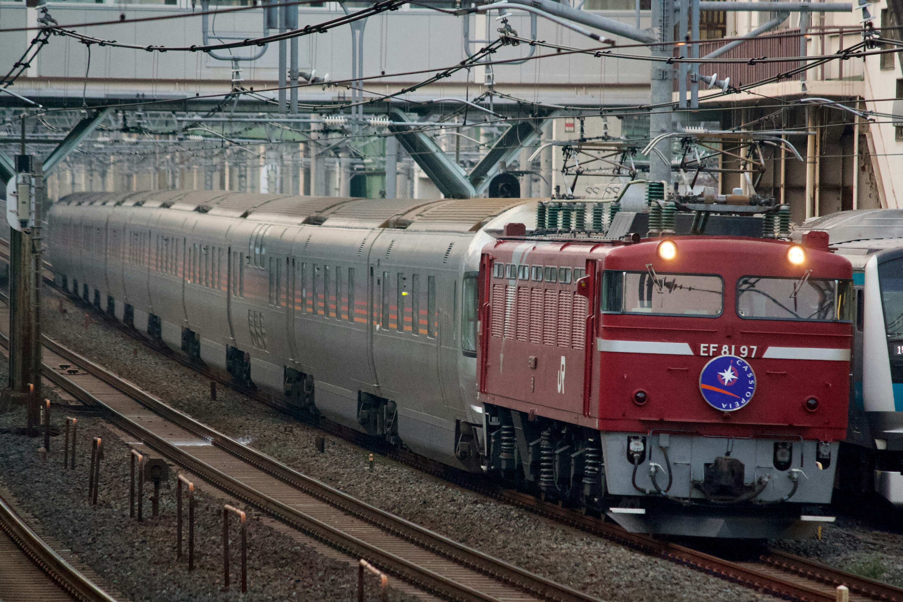 赤い機関車が長い列車を牽引している風景