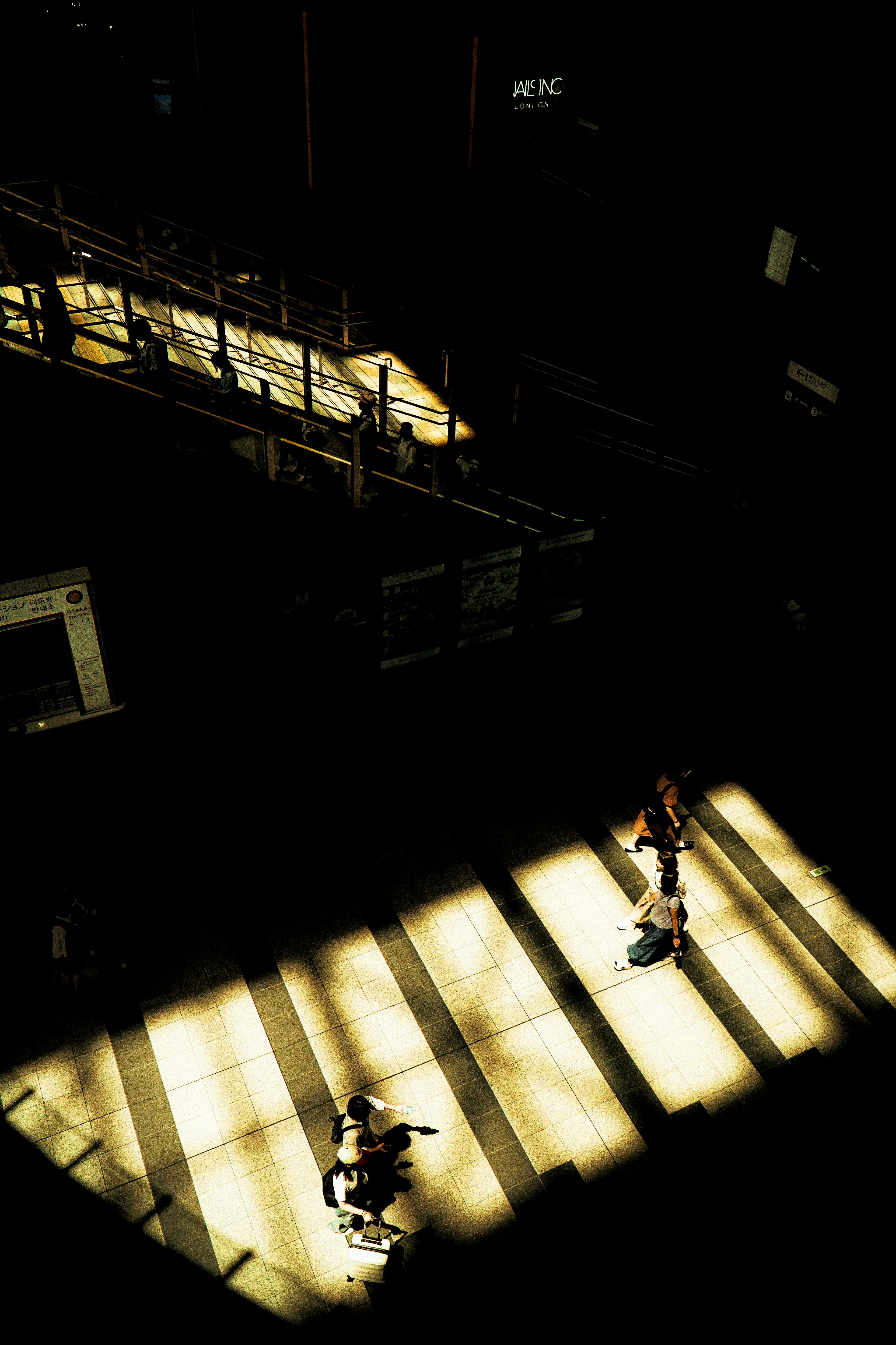 Silhouettes de personnes marchant dans un espace sombre illuminé par la lumière