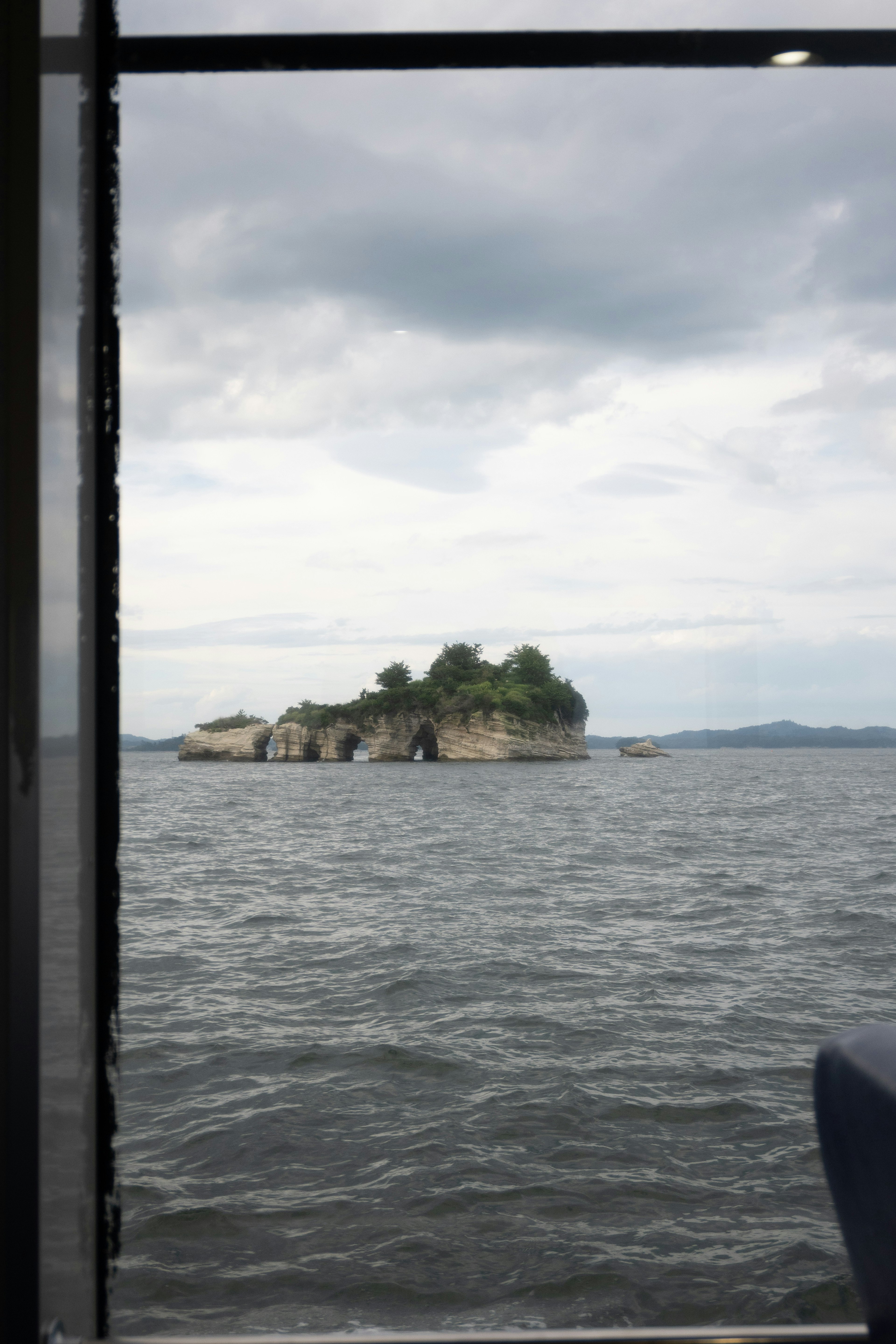 Pulau kecil dikelilingi air di bawah langit mendung