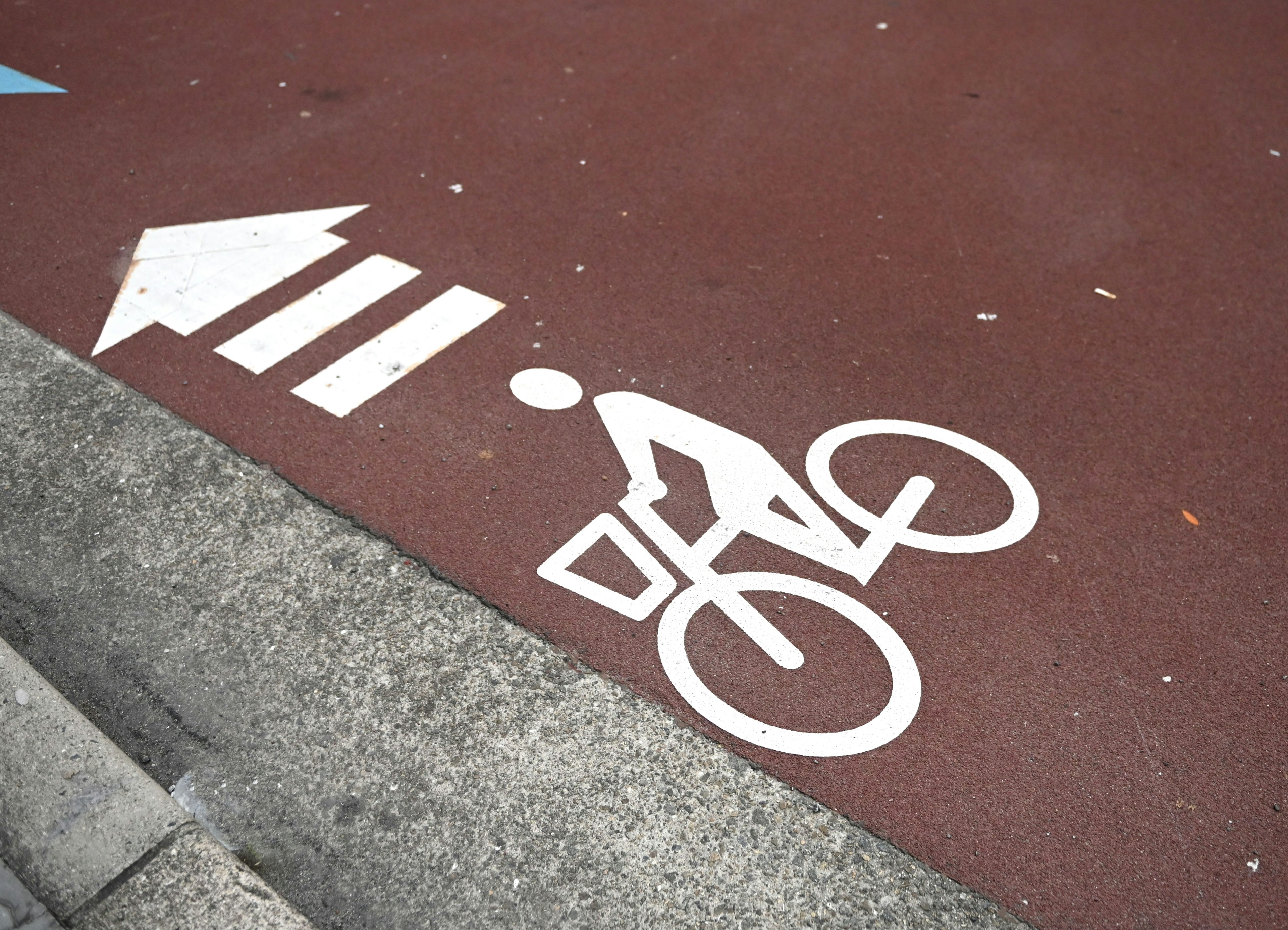 Simbolo di bicicletta bianco e freccia su una pista ciclabile rossa