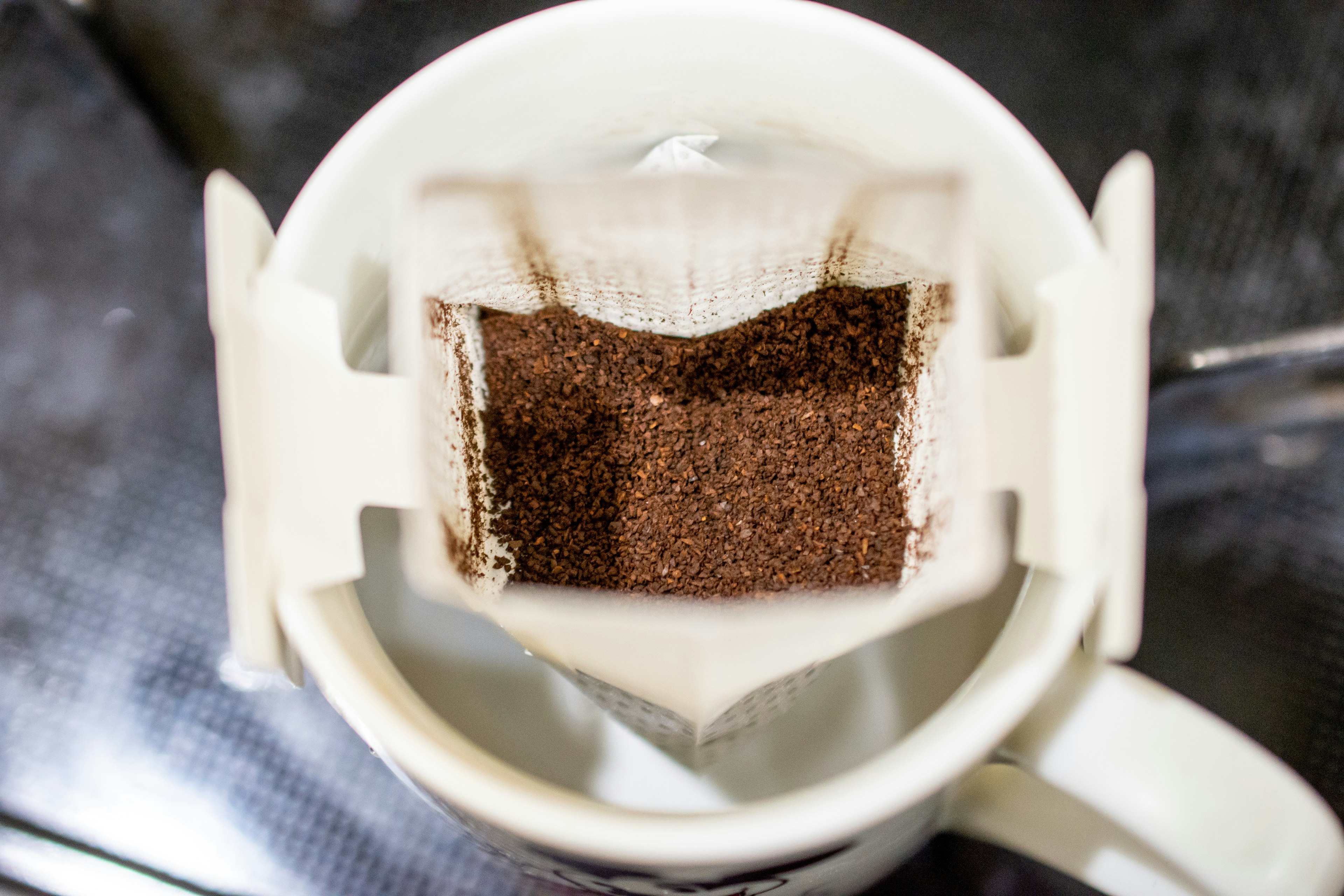 Close-up shot of a coffee filter with ground coffee inside a mug