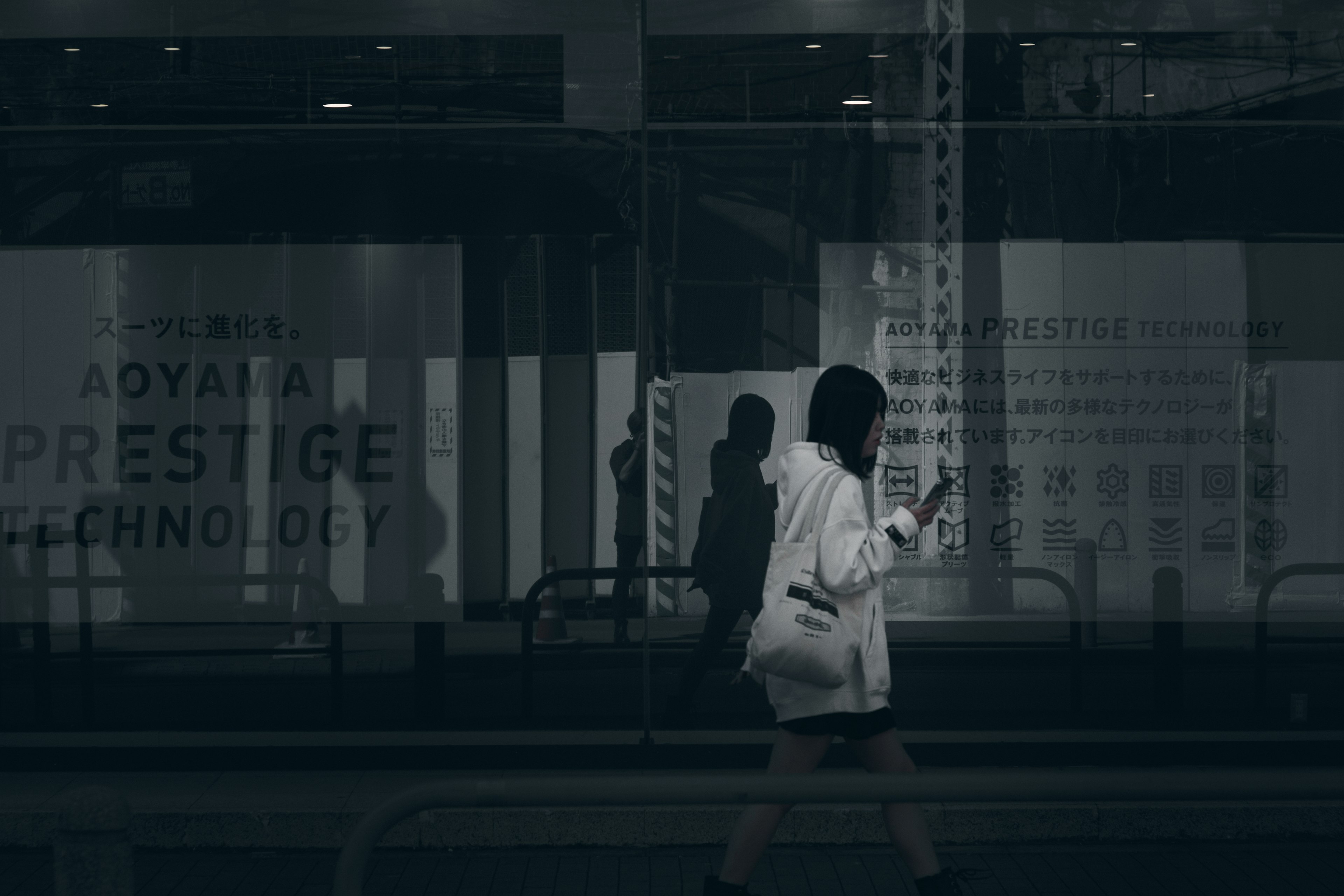 Una mujer con chaqueta blanca caminando frente a una vitrina con reflejos