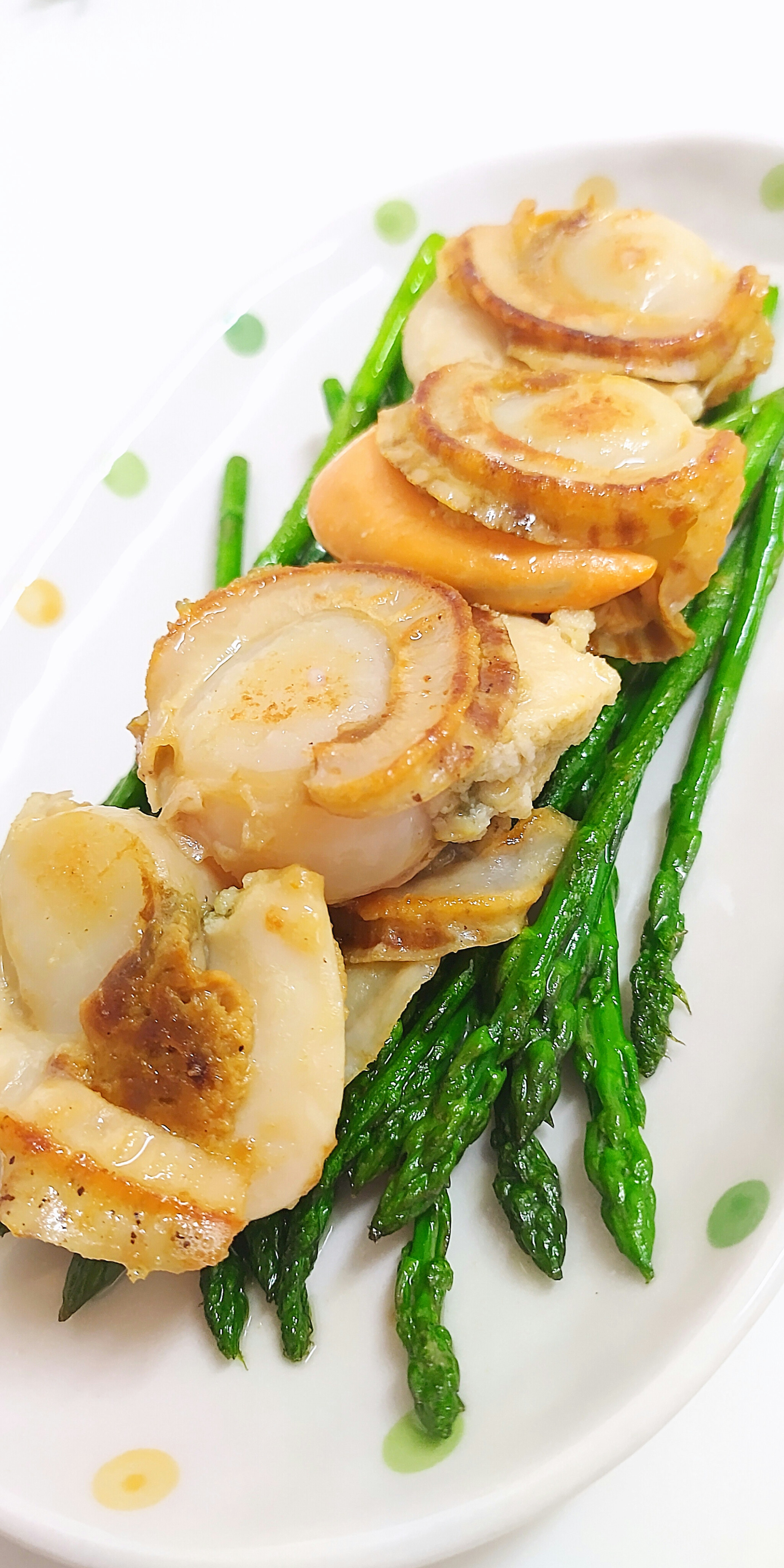 Dish of seared scallops arranged on asparagus