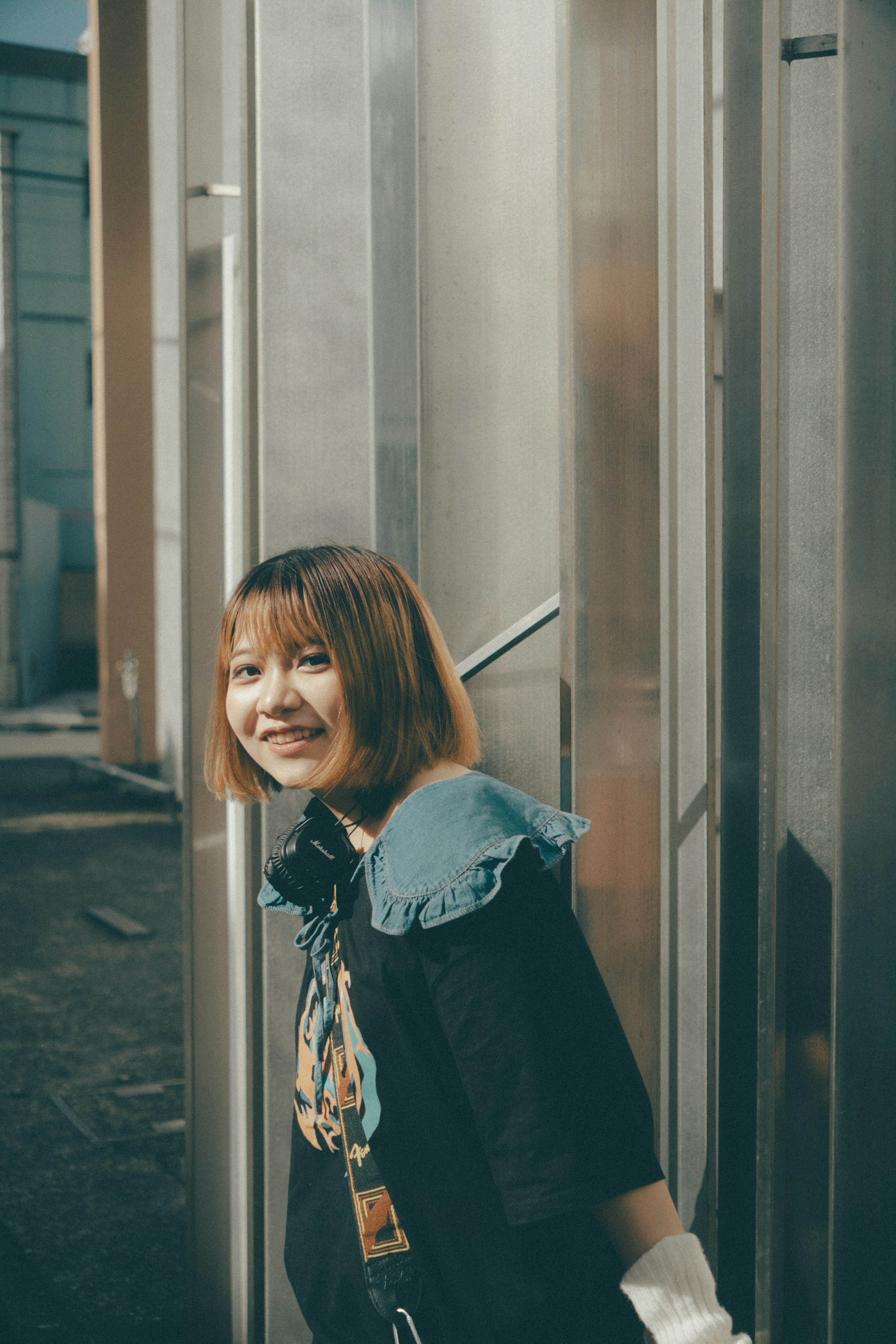 A smiling woman with short hair in a casual outfit against a metallic background