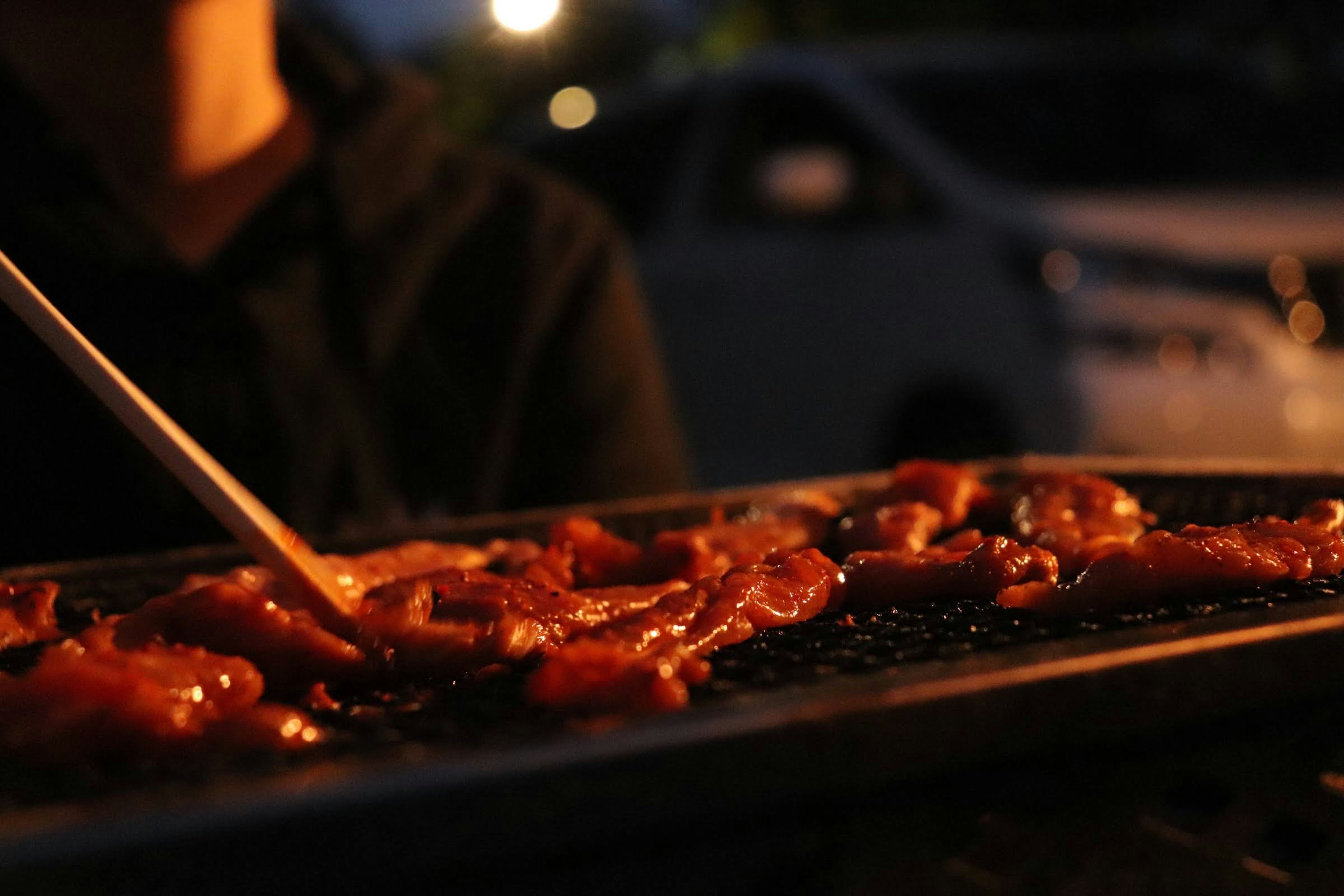 밤에 구운 고기의 사진 손에 그릴을 들고 맛있게 조리된 고기