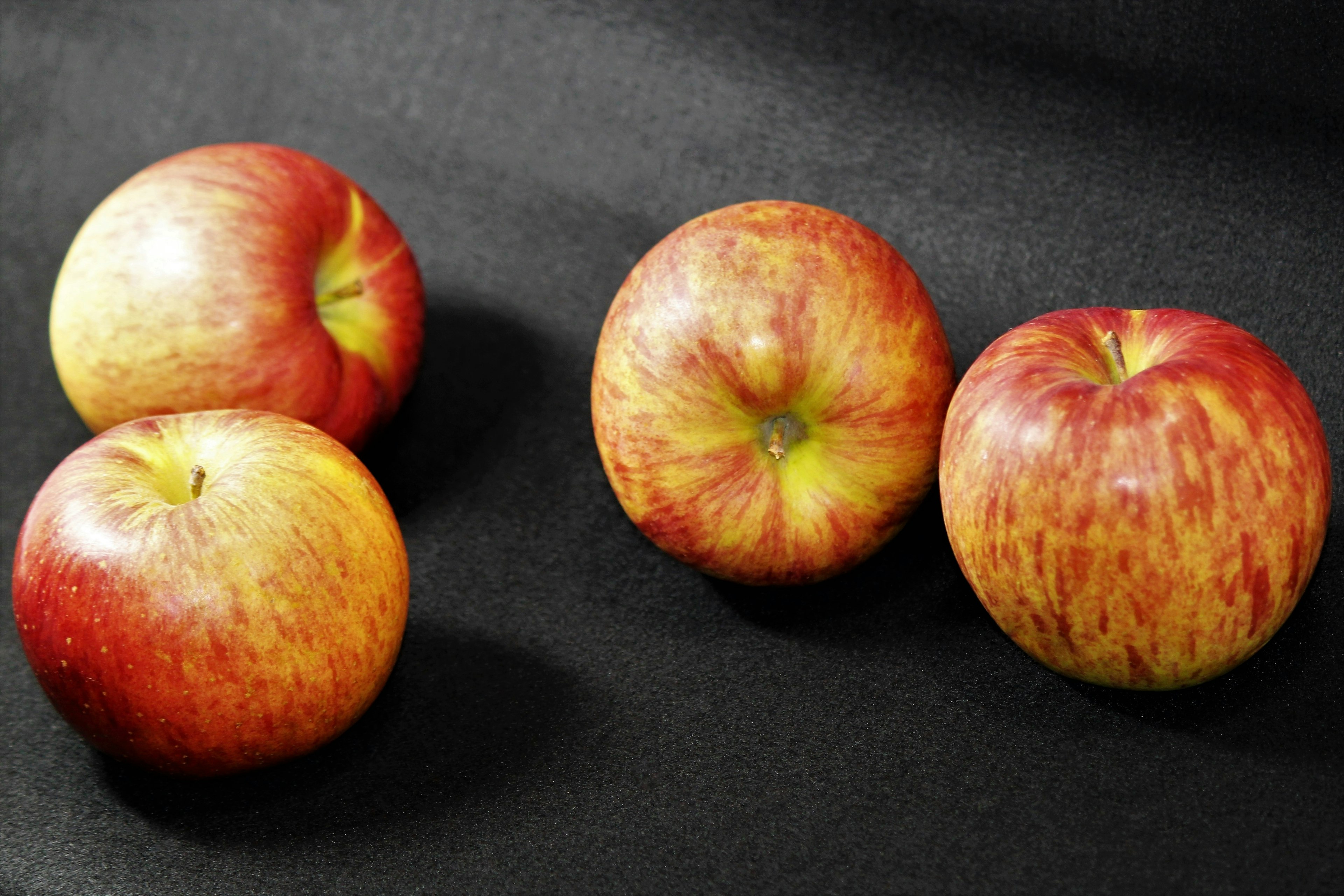 Manzanas rojas y amarillas colocadas sobre un fondo negro