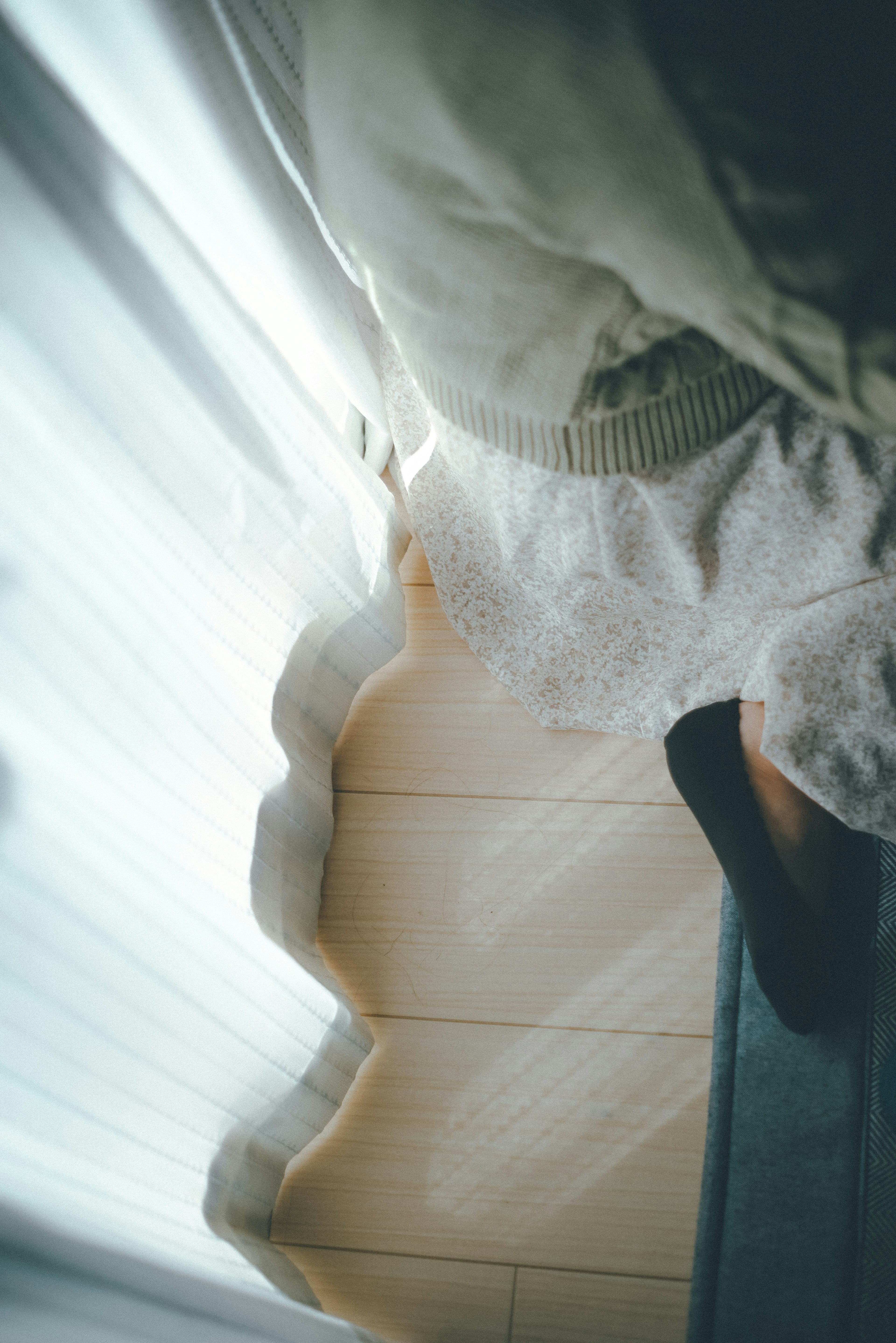 Imagen que muestra parte de una habitación con cortinas suaves y suelo de madera