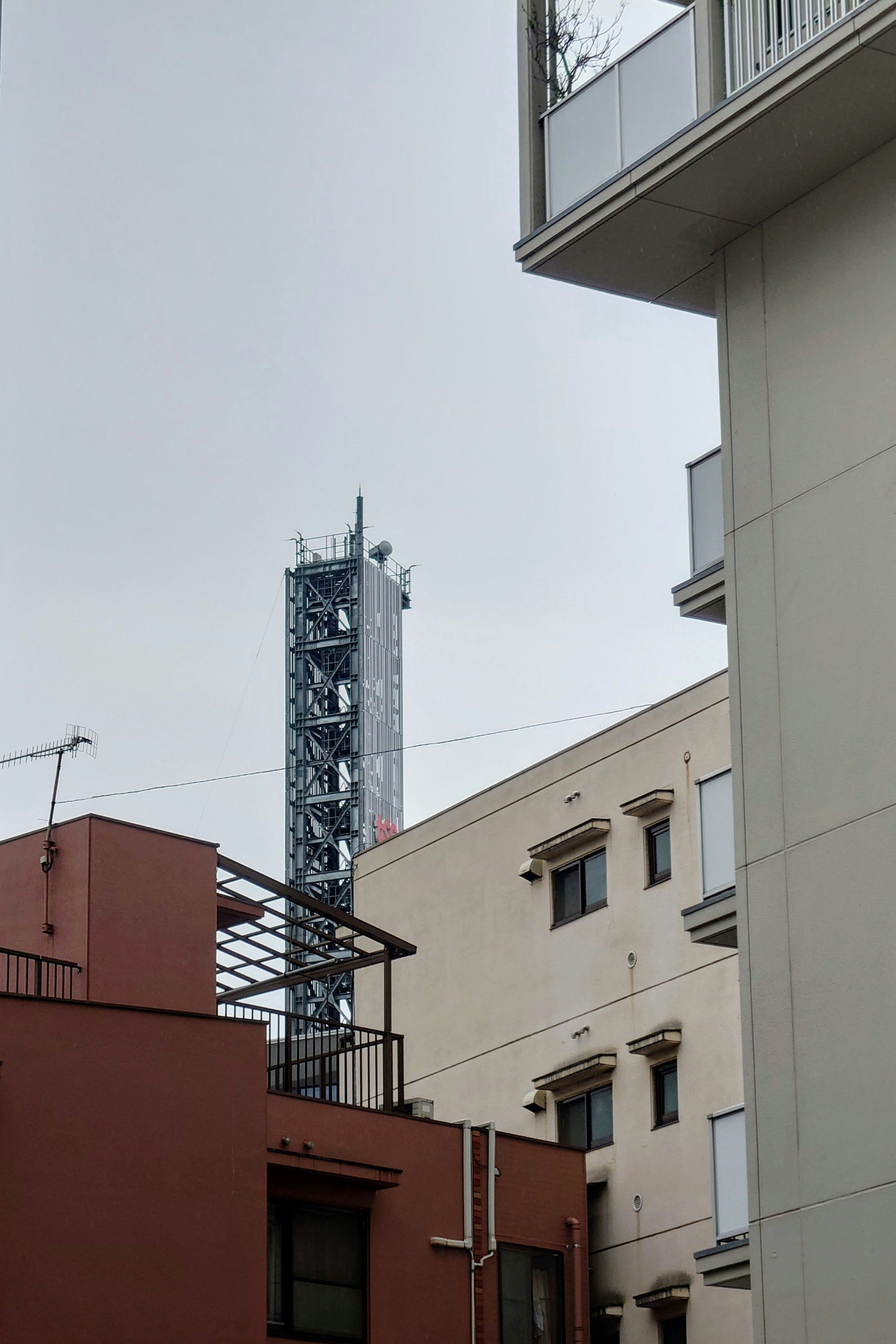 Torre di comunicazione visibile tra gli edifici sotto un cielo nuvoloso