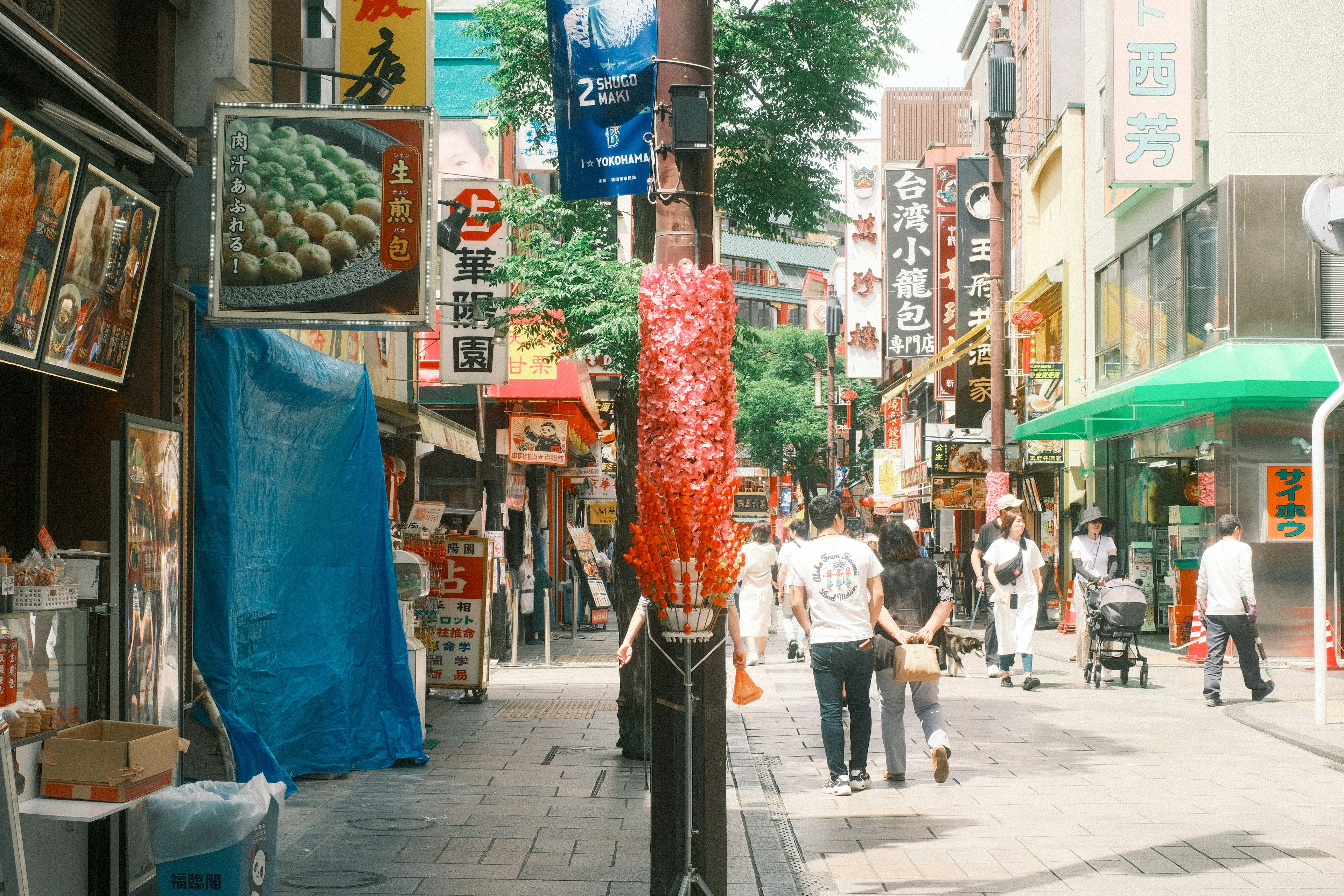 賑やかな商店街の通りに人々が行き交い、色とりどりの看板と露店が並んでいる