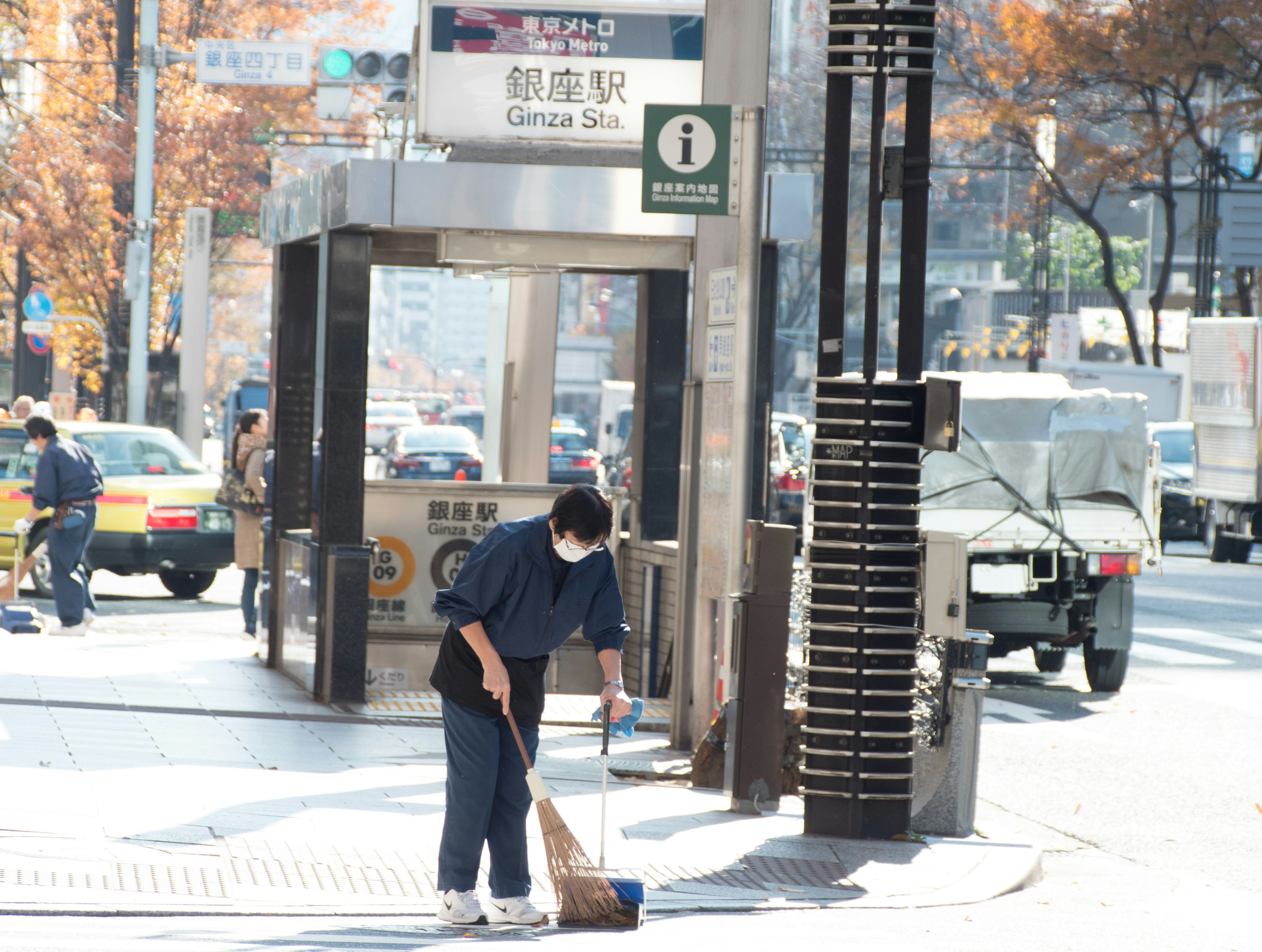 Travailleur balayant la rue près d'une station de métro