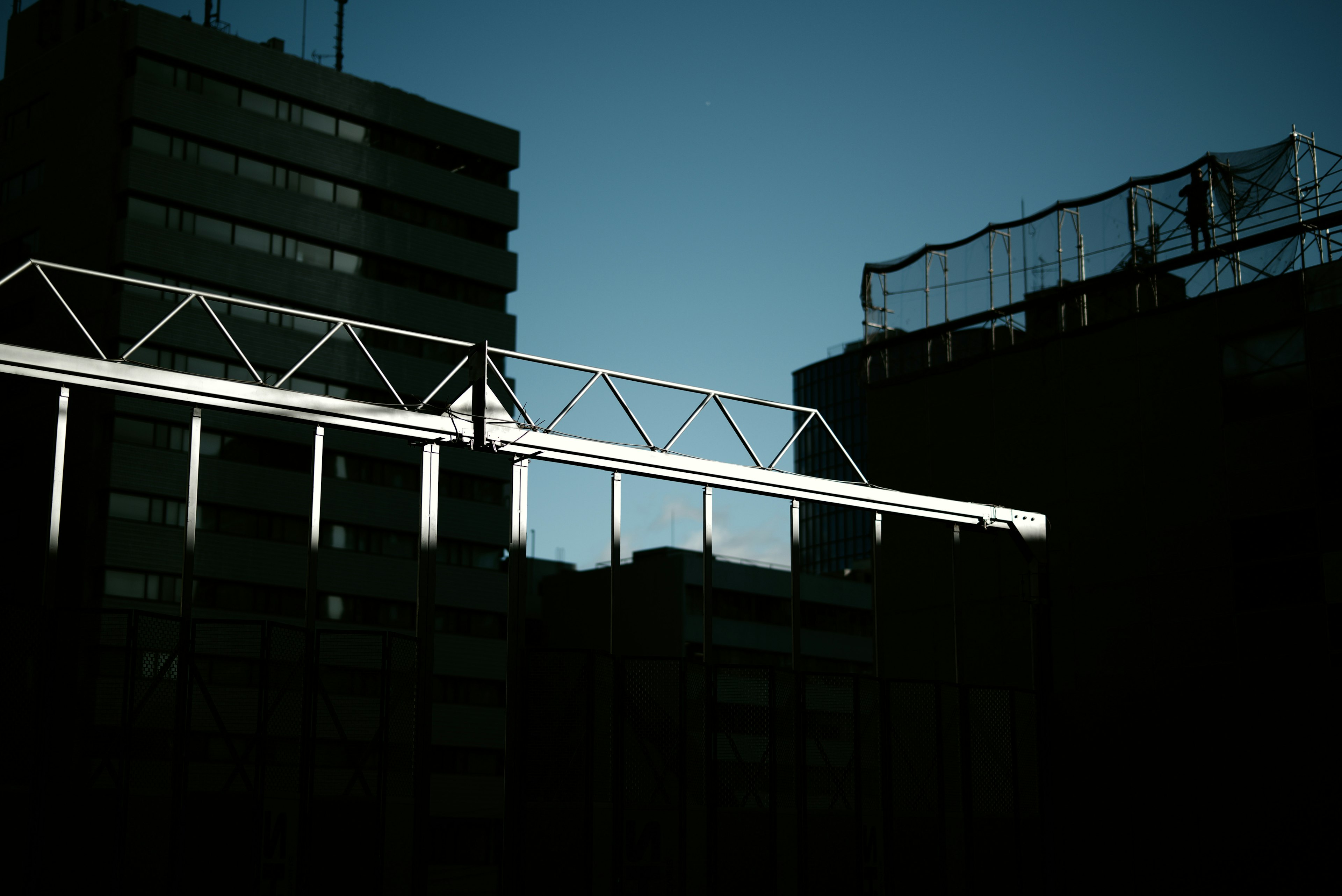 Silhouette de bâtiments urbains et structure métallique contre un ciel crépusculaire