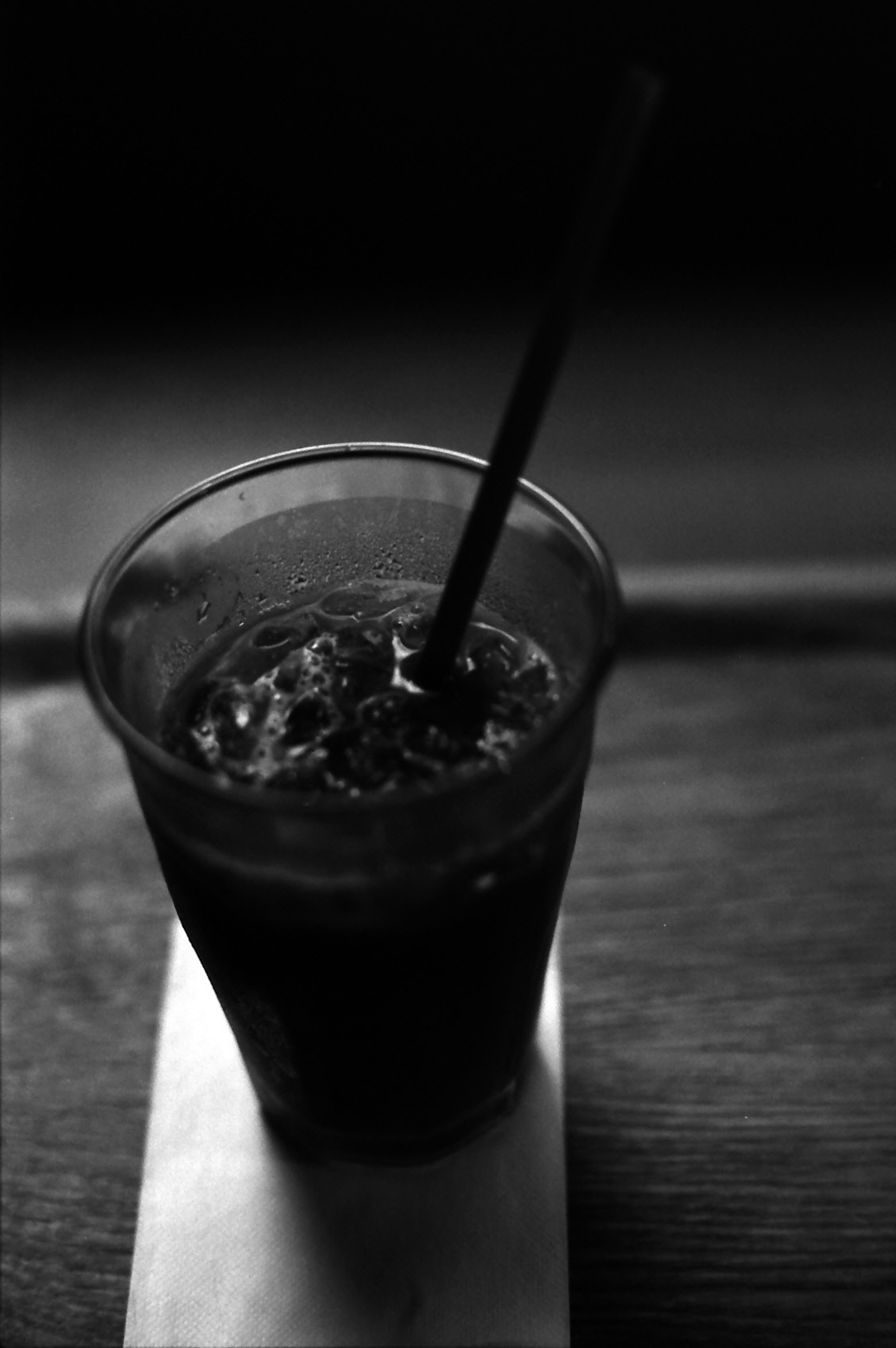 Black and white image of a drink in a cup with a straw