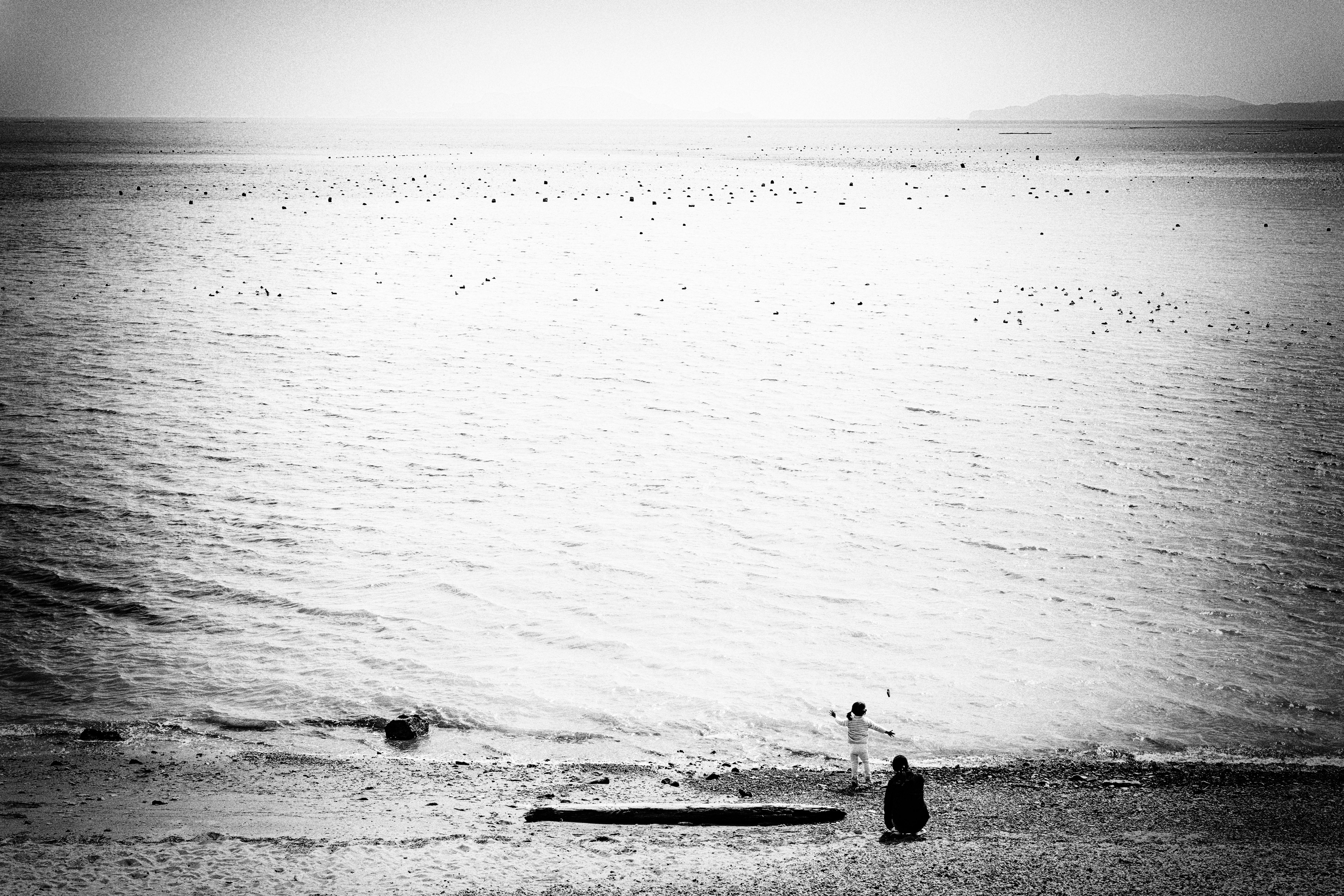 Siluetas de un niño y un adulto jugando en la playa en un paisaje en blanco y negro