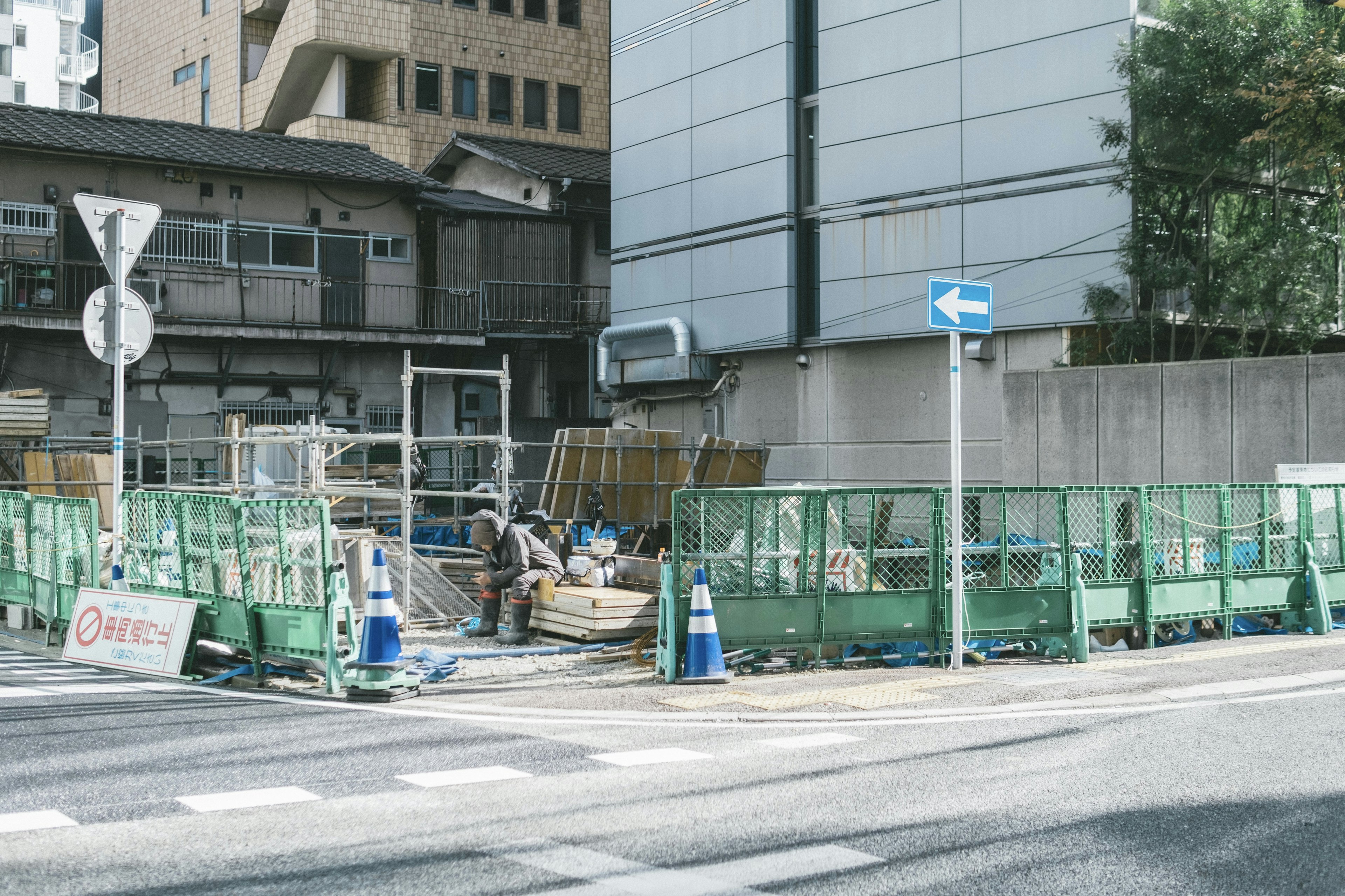 Construction site with green fences and workers visible